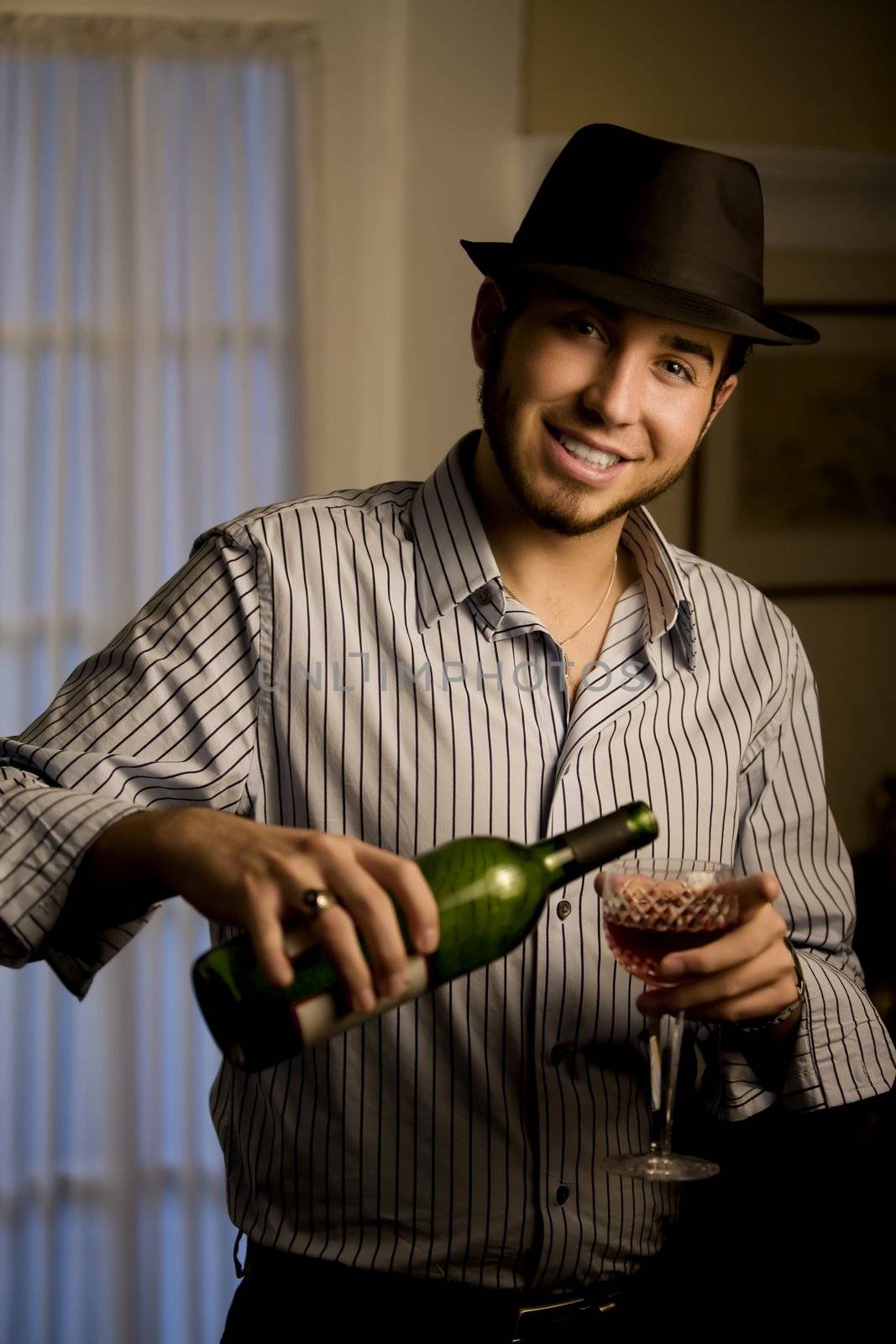Handsome Young Man Indoors Wearing a Fedora Hat and Red Wine