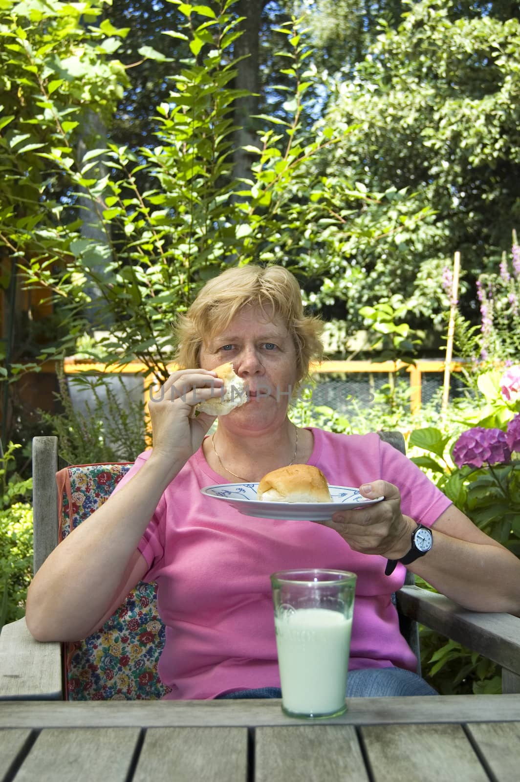 elderly woman is having lunch in the garden by ladyminnie