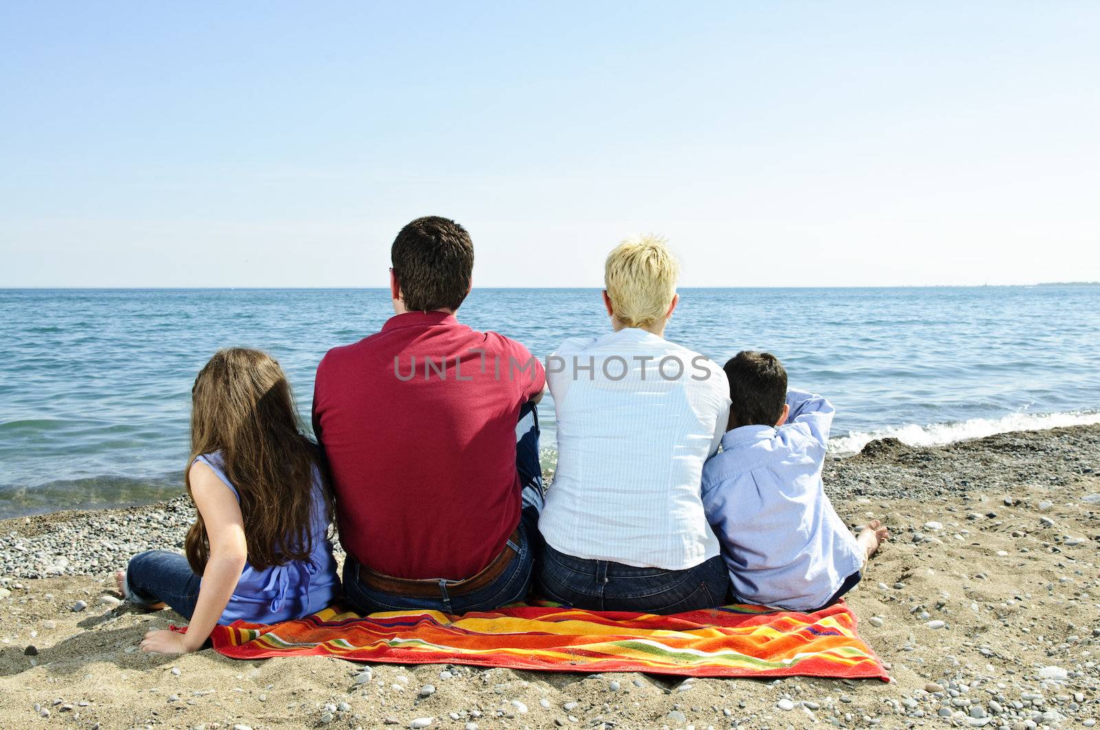 Family sitting on towel at sandy beach