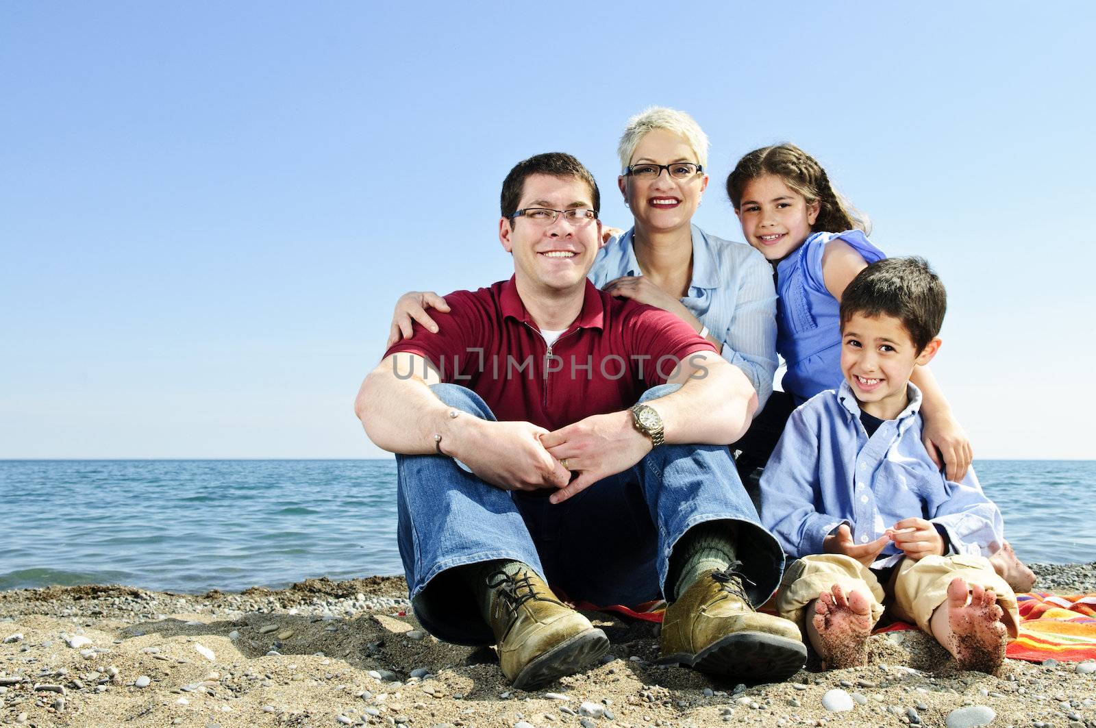 Happy family sitting on towel at sandy beach