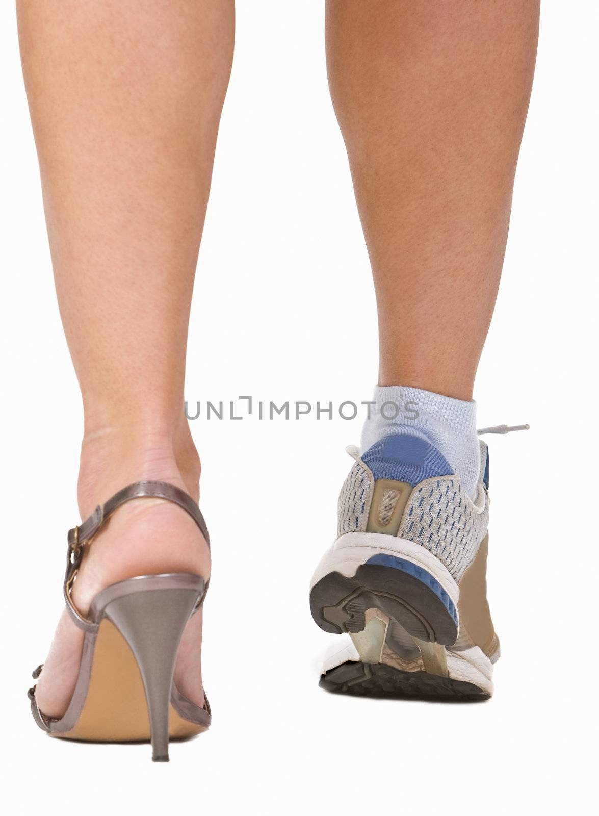 Image of a woman's legs as she is wearing a highheel sandal and a sports shoe. Conceptual abstract image which emphasizes the importance of sport.