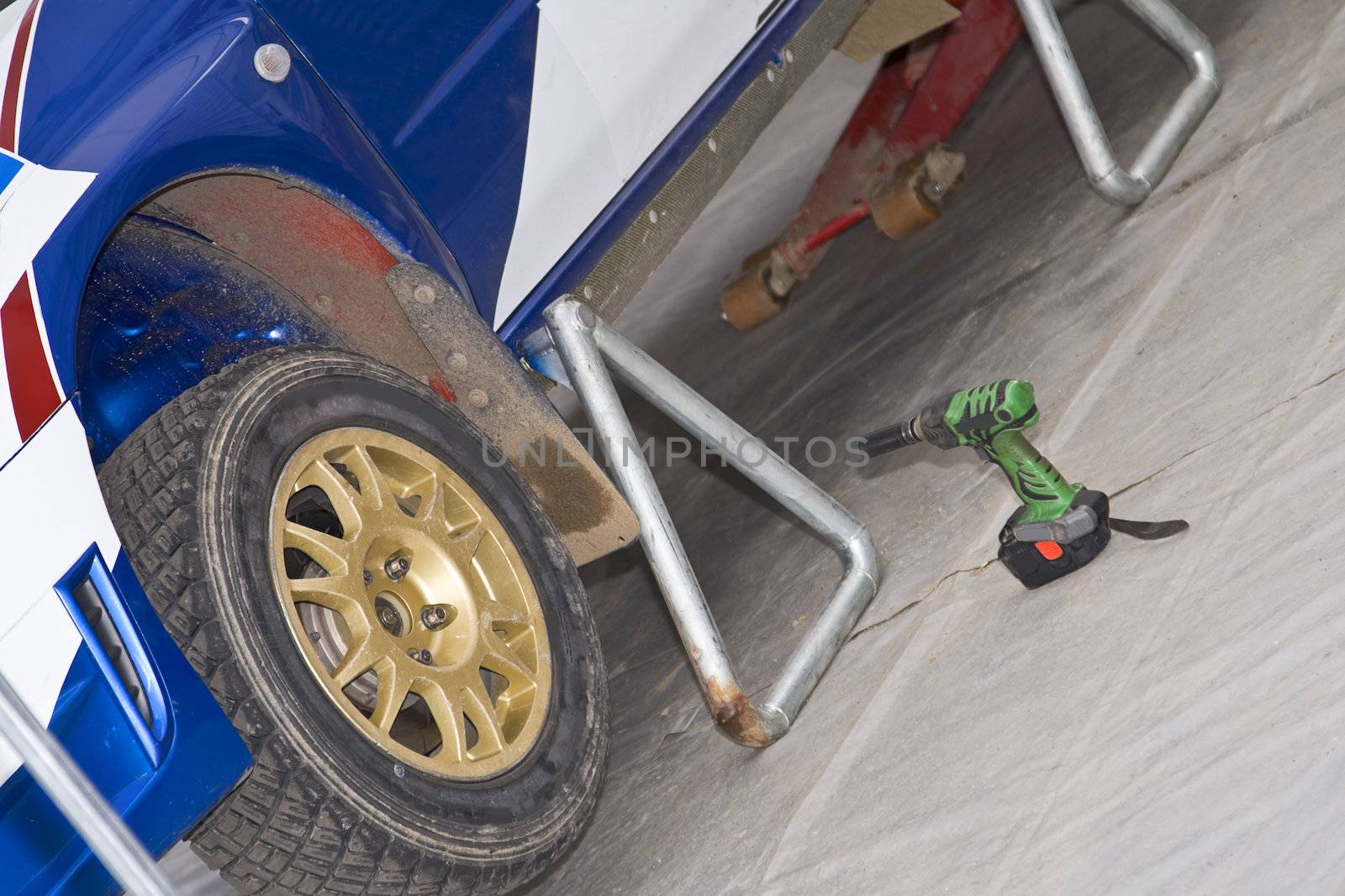 Detail of a rally car wheel and some tools at the pit stop.