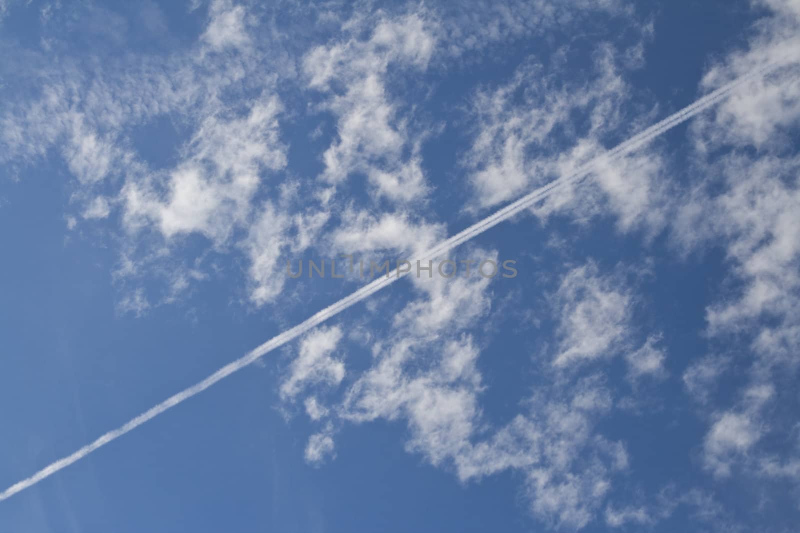 Airplane traces over a blue cloudy sky 