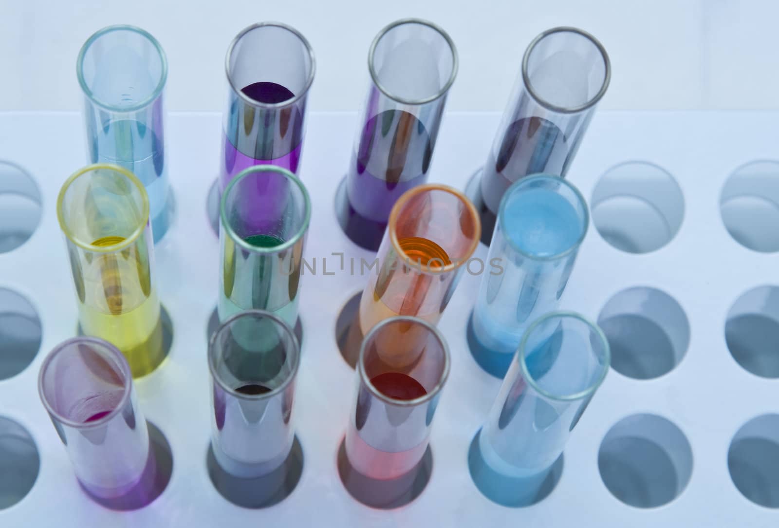 Upper view of some testtubes with colorful solutions in a stand.