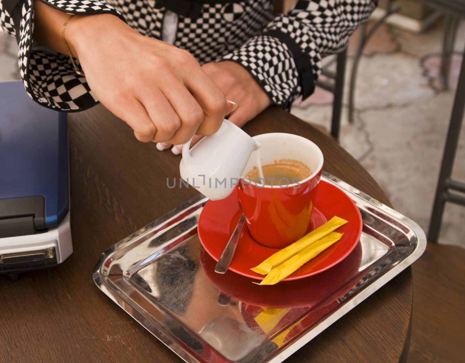 Close-up of a businesswoman's hands as she is preparing coffee latte on a terrace.
