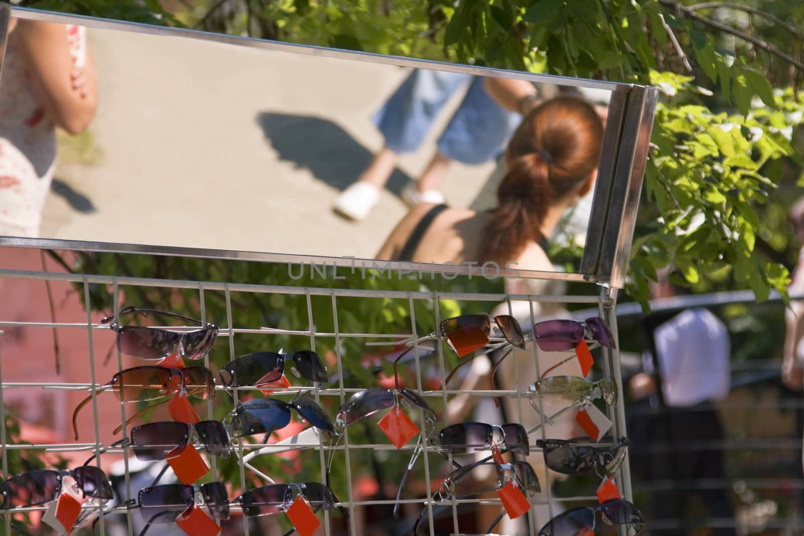 Interesting summer street abstract image of a sunglasses stand and people's reflections in the mirror.