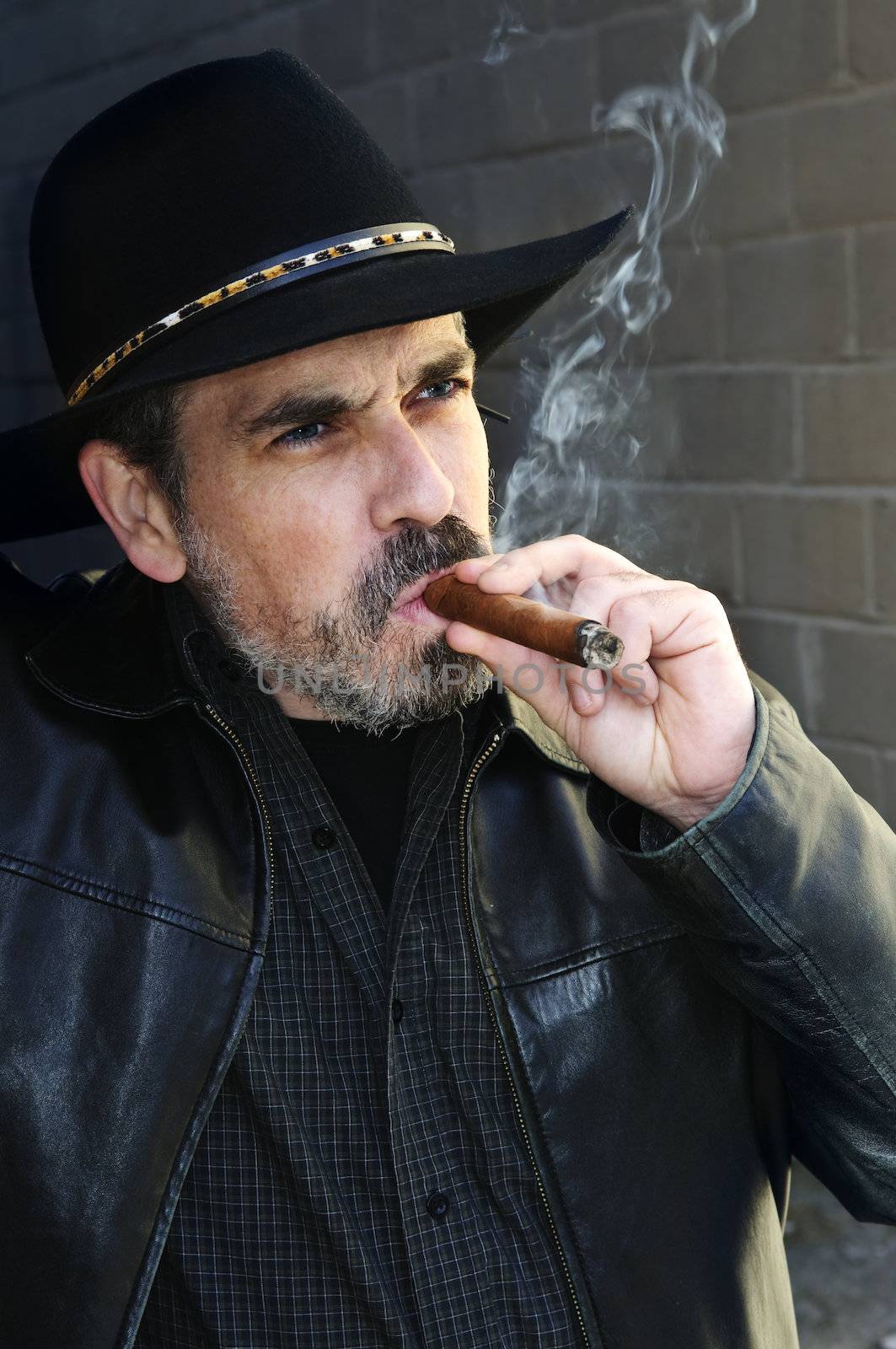Man with beard in cowboy hat smoking cigar