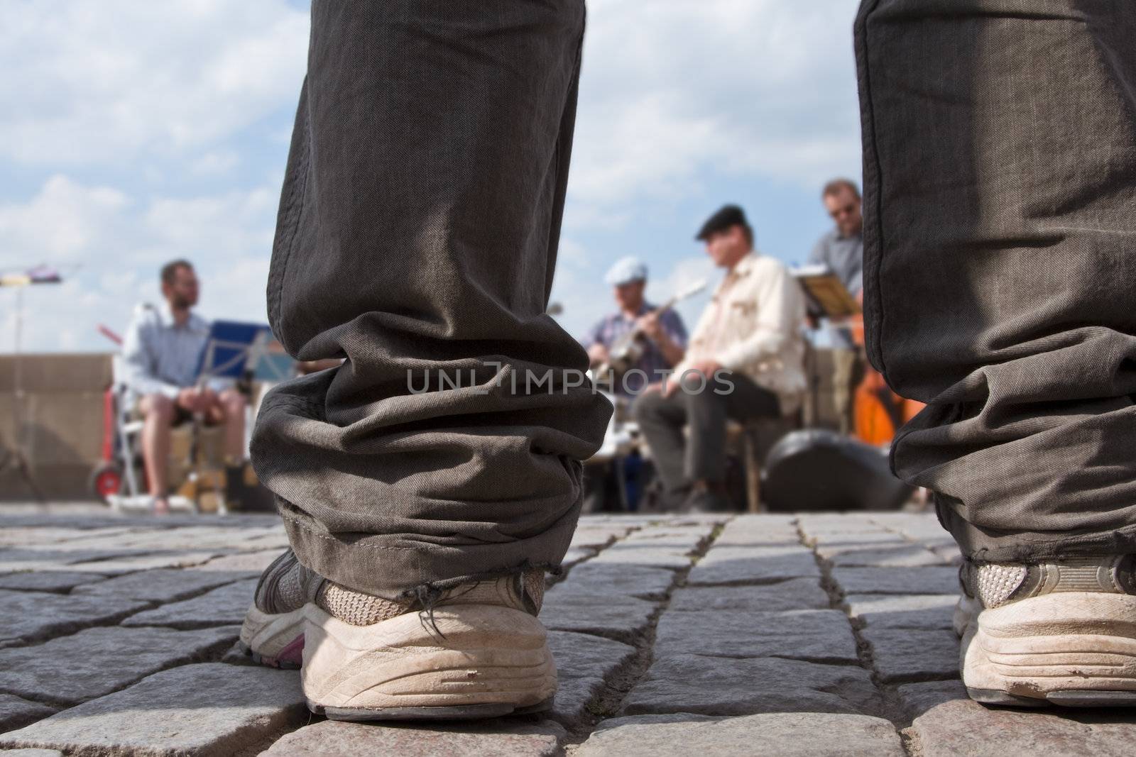 Image of a boy's legs as he is looking to a Jazz street band performing.