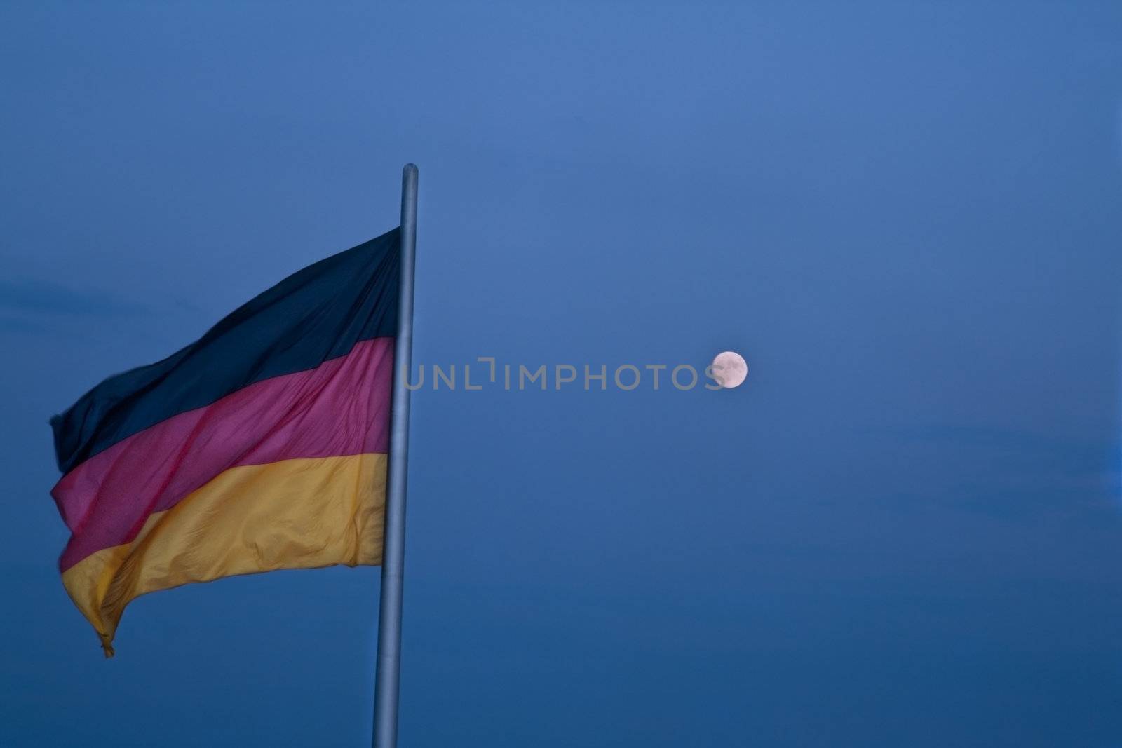 The German flag and the moon against a blue dusk sky. 