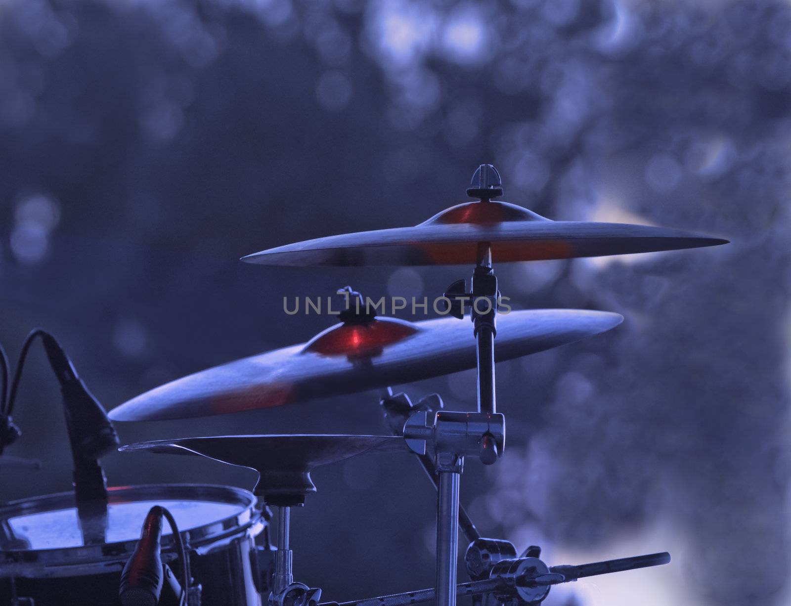 Image of cymblas and drum during a rock concert with specific lighting.