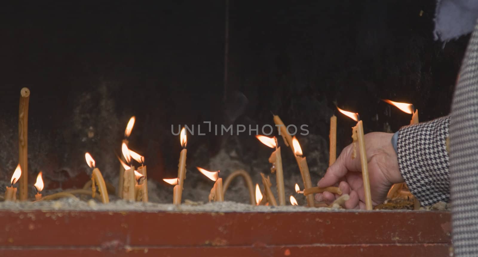 Old woman lighting candles in remembranse of the departed ones
