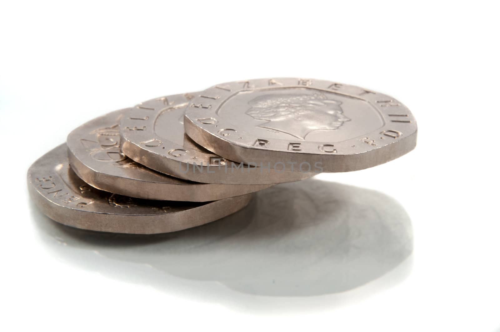 Close and low level of a small stack of British twenty pence coins arranged over white.