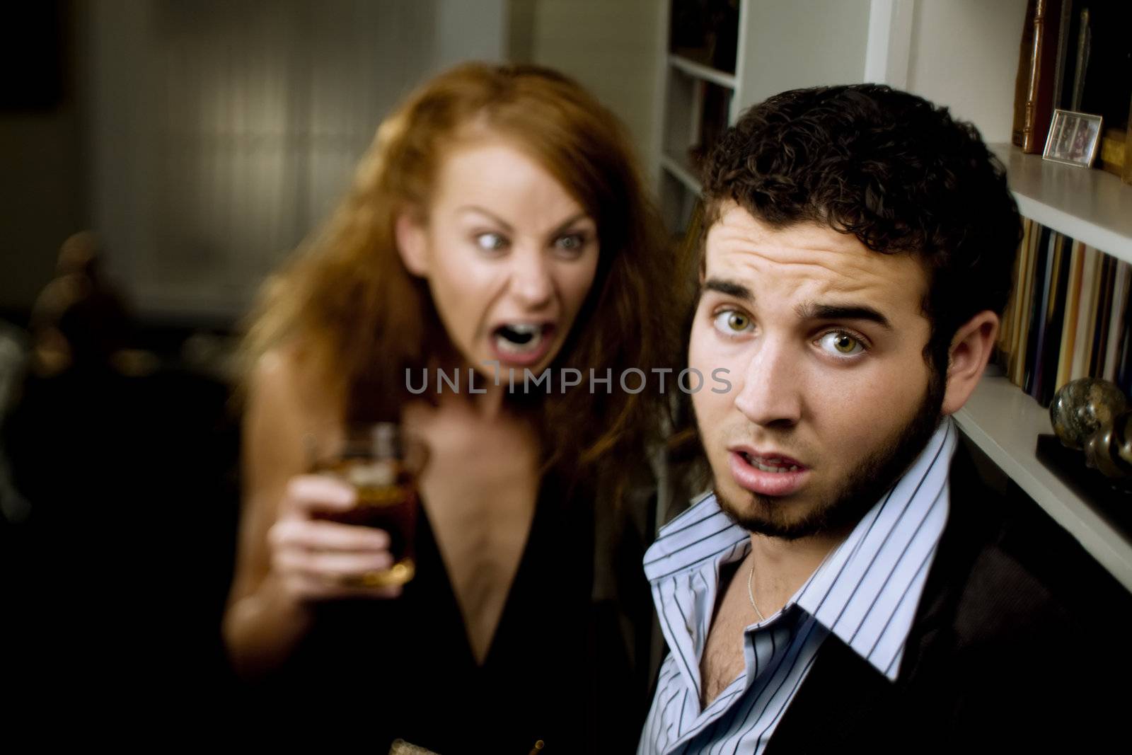 Young woman with cocktail yells at a man at party