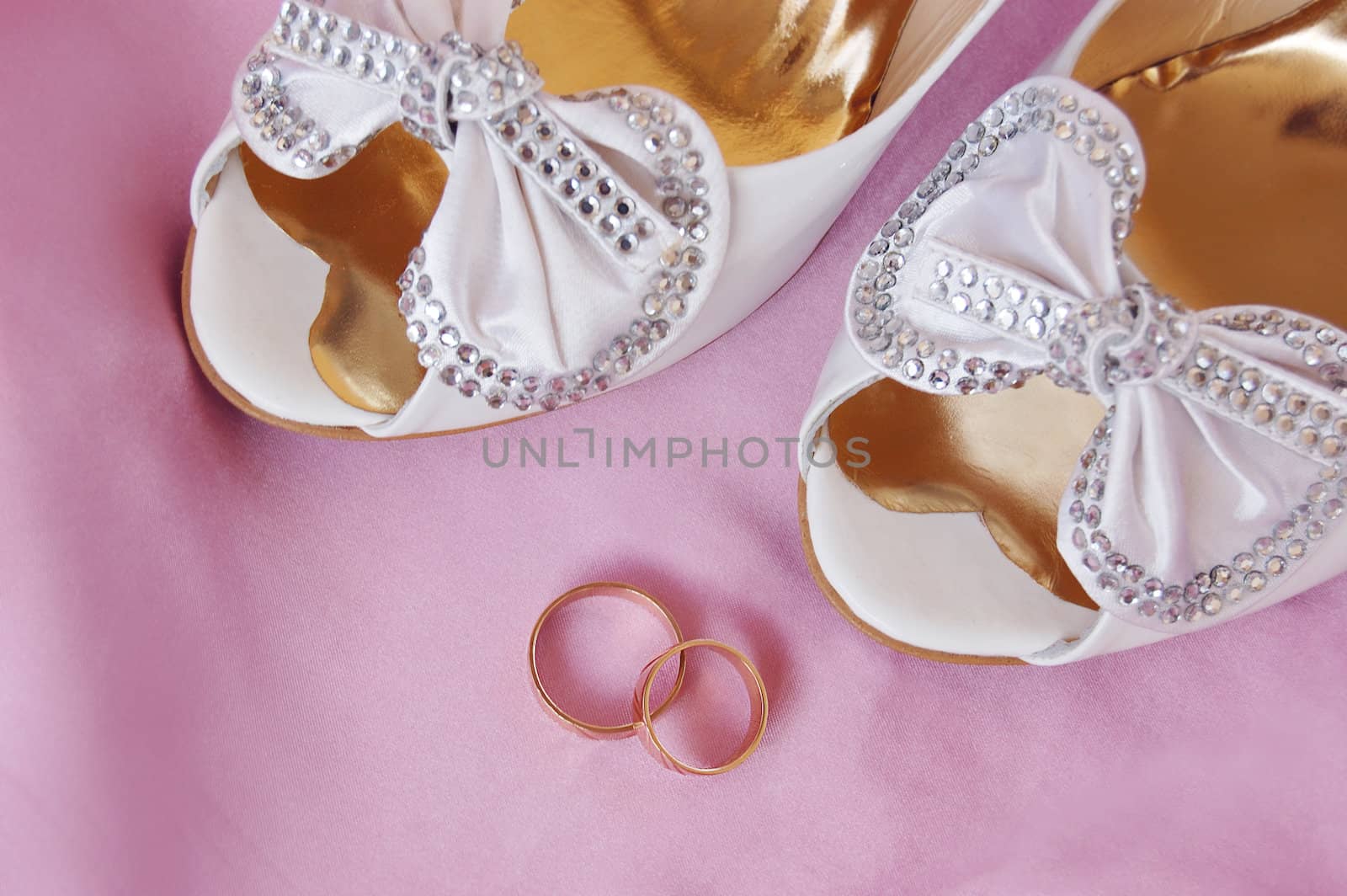 bridal shoe heel on wedding rings, pink background