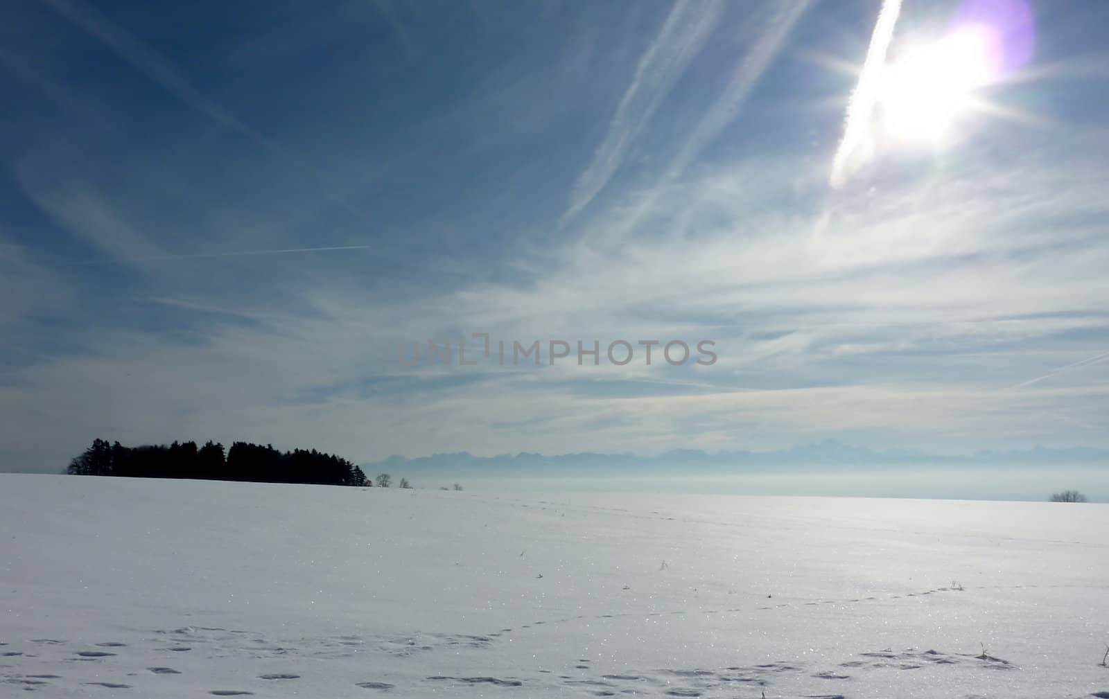 View of the Alps over a snowy hill and with sun