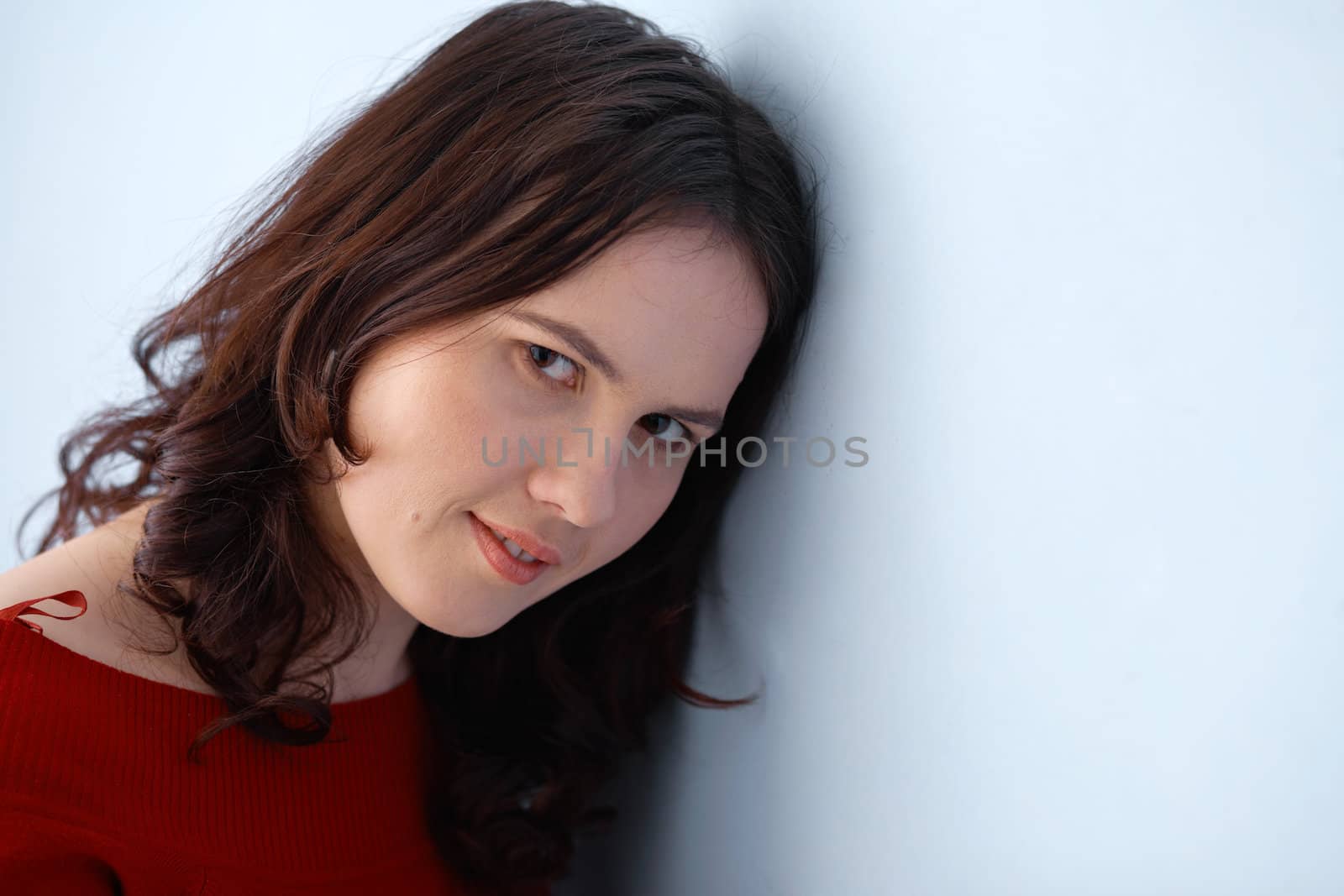 Closeup portrait of a young beautiful woman leaning on the wall