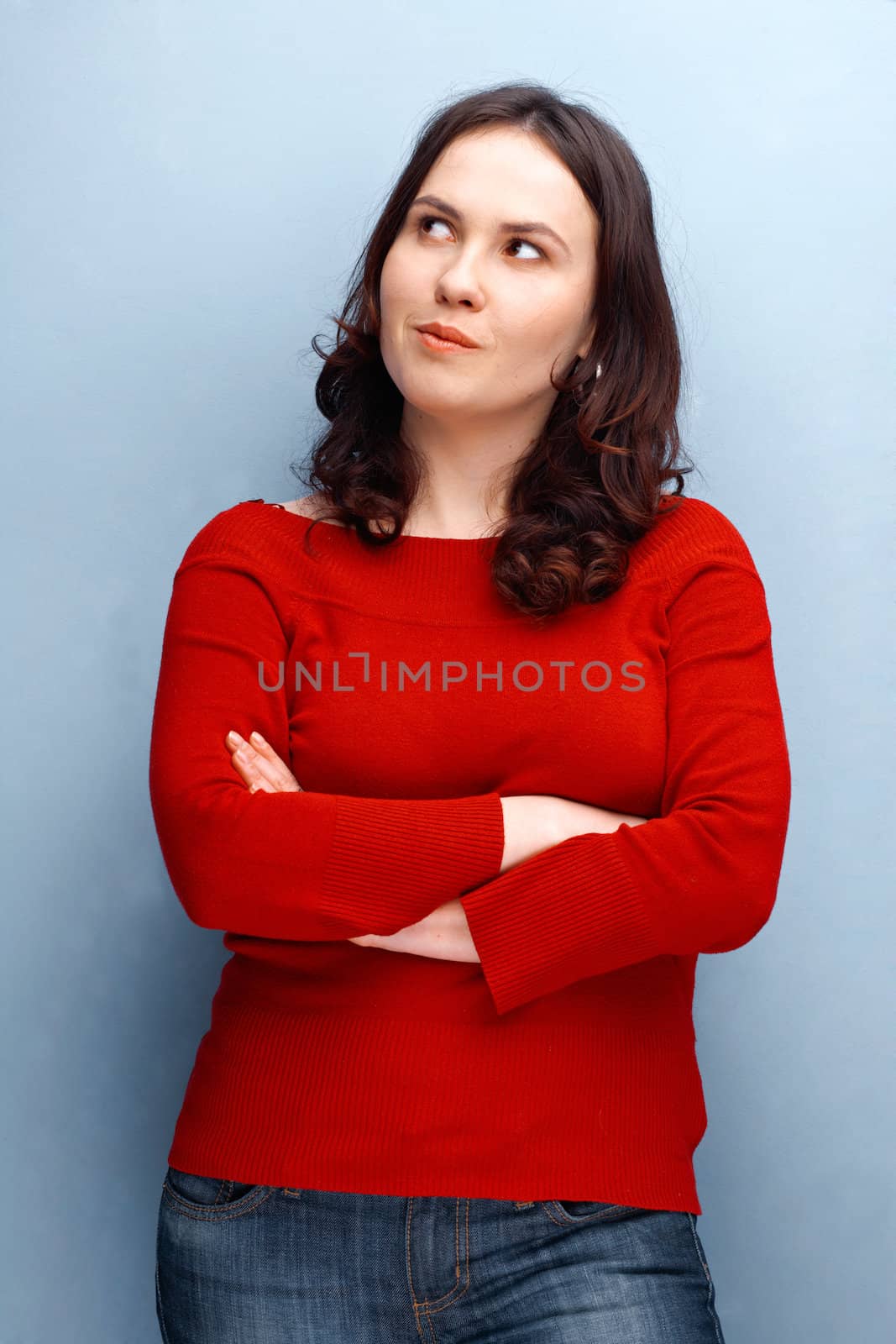 Young woman  in red jersey looking away with her hands folded 