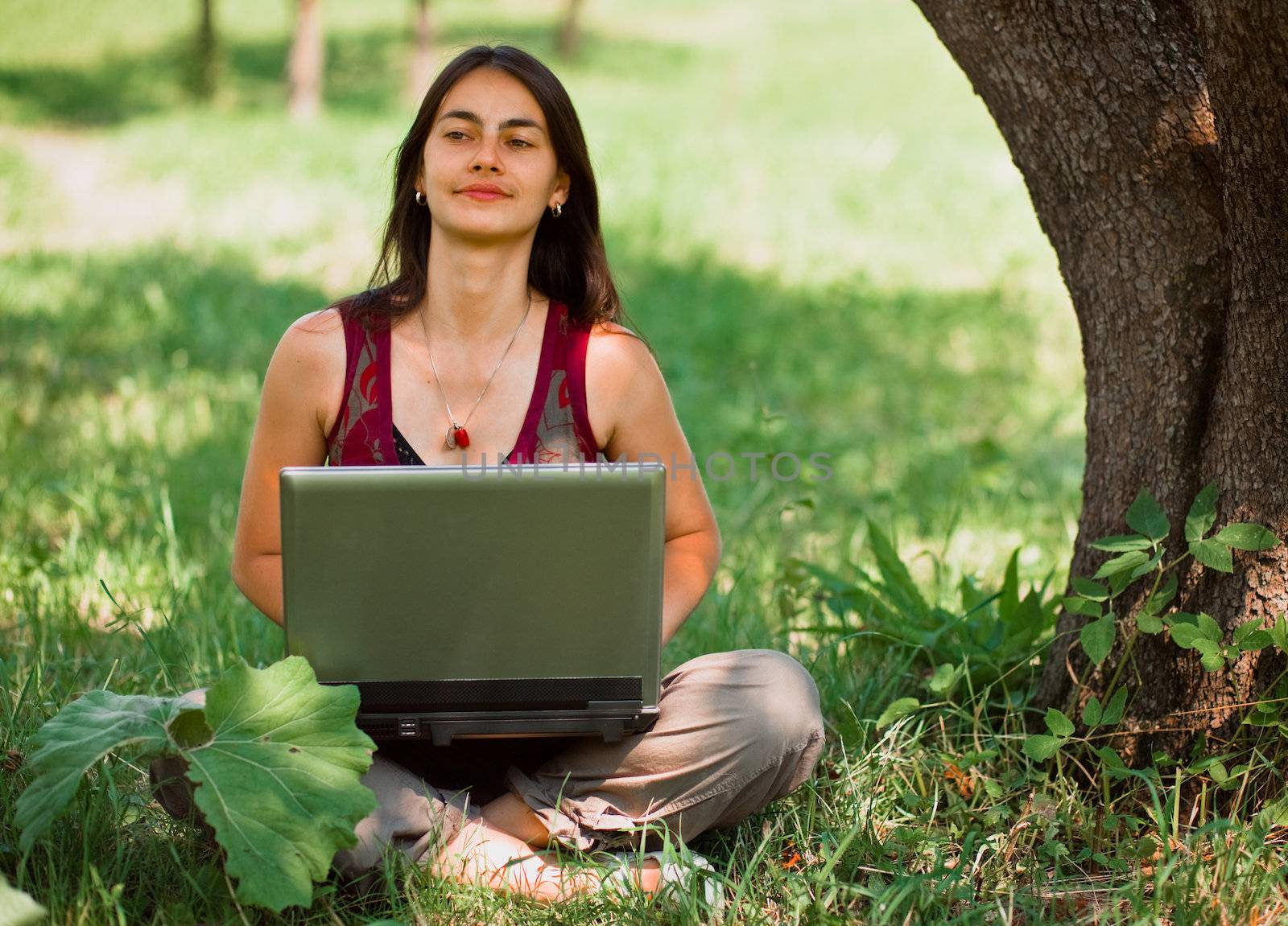 Happy young woman using her laptop outdoors. by romanshyshak