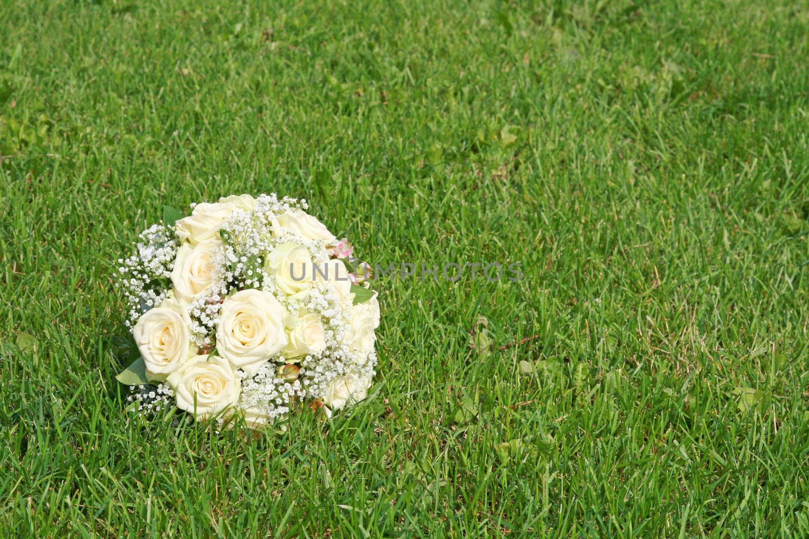 Wedding bouquet from white roses on a green grass