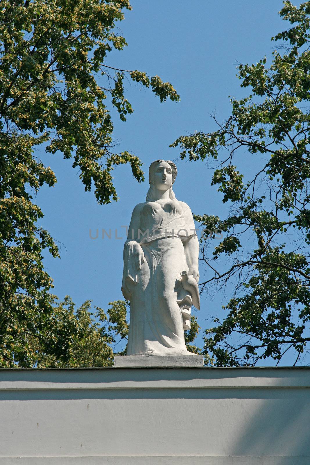 Sculpture on a background of the sky in a frame of branches of a tree