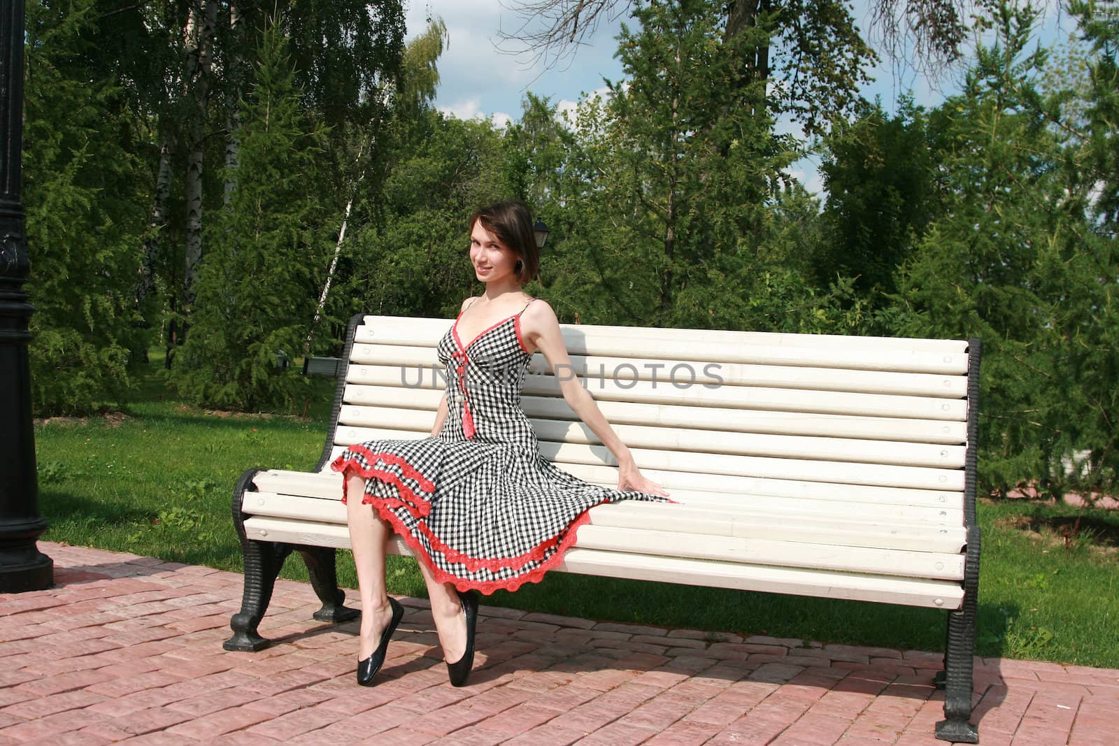 The girl sits on a bench and coquettishly poses