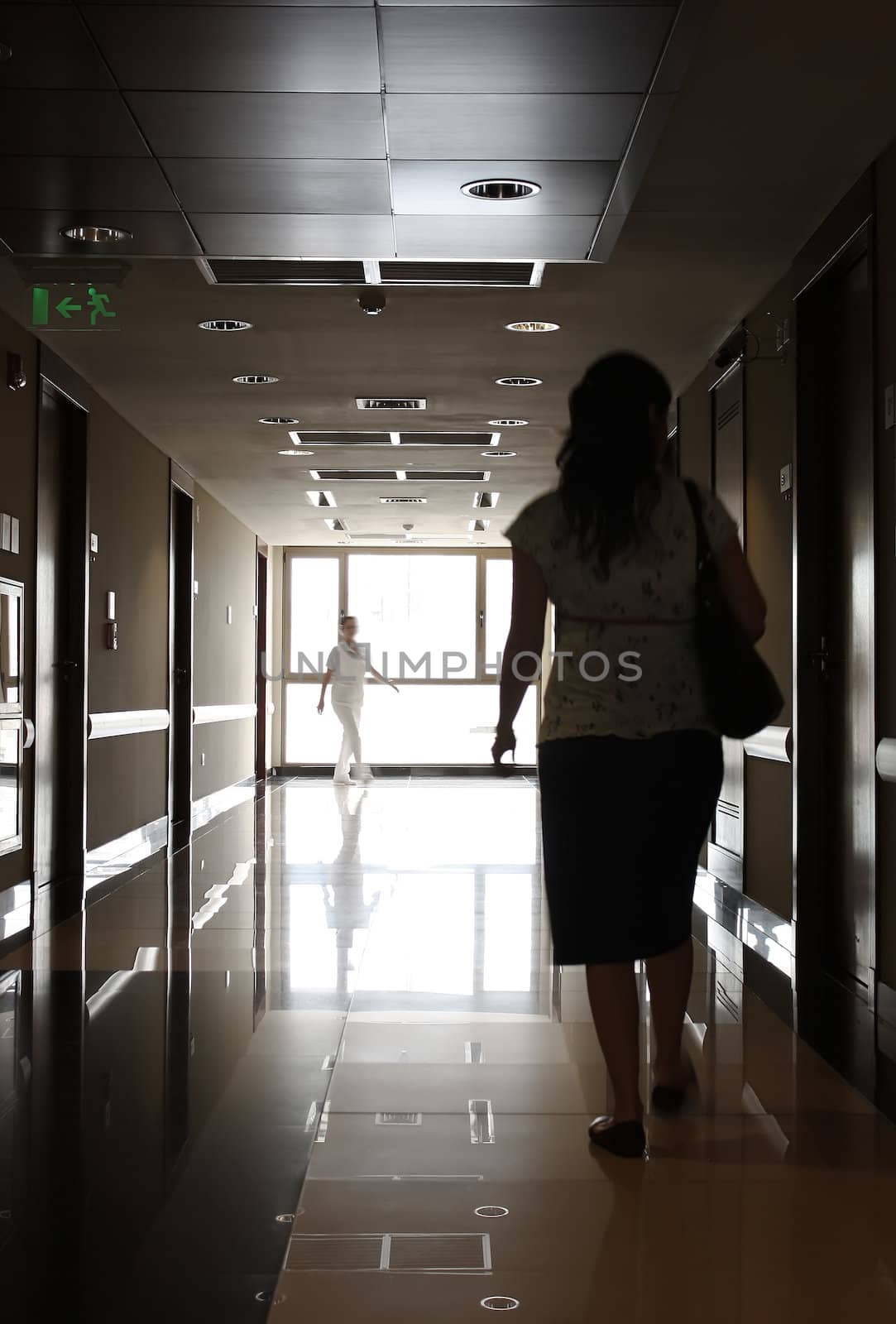 Patient and nurse walking at hospital corridor