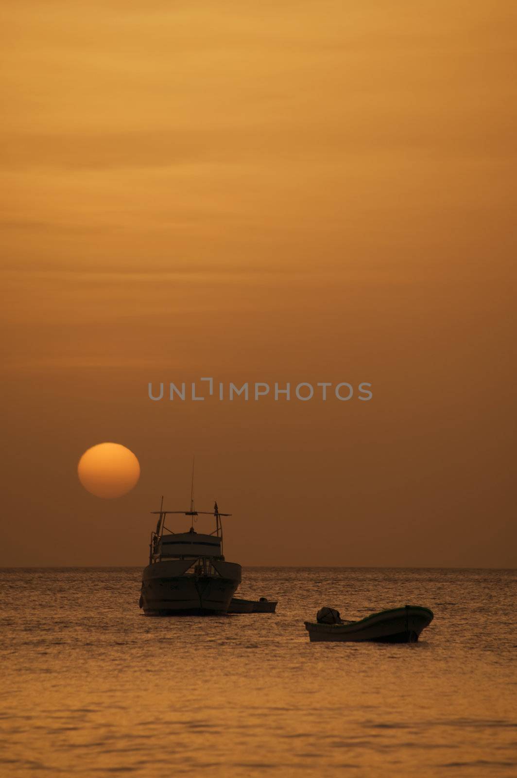 Two boats in front of a setting sun at dusk