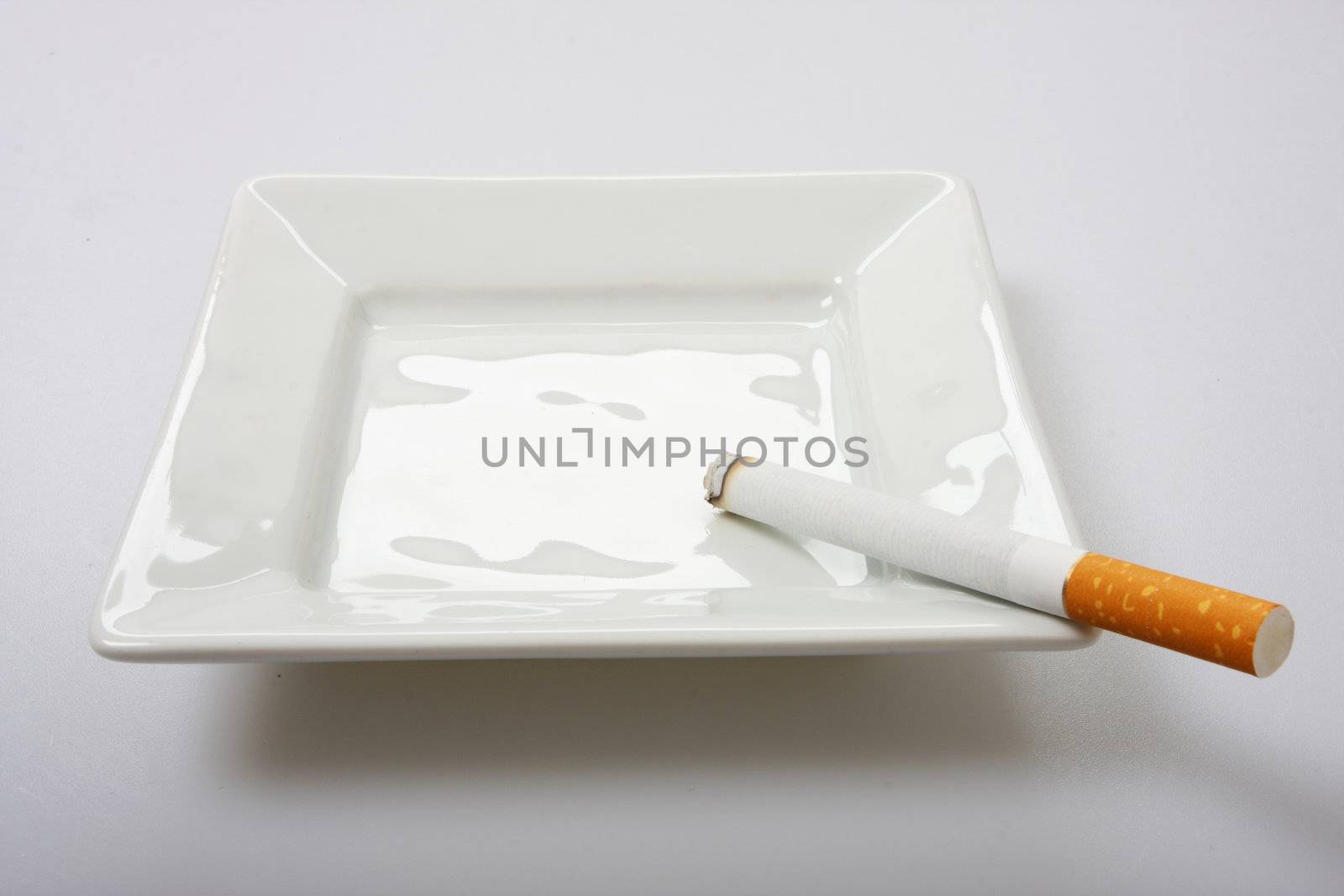 burning cigarette on white ashtray isolated on white