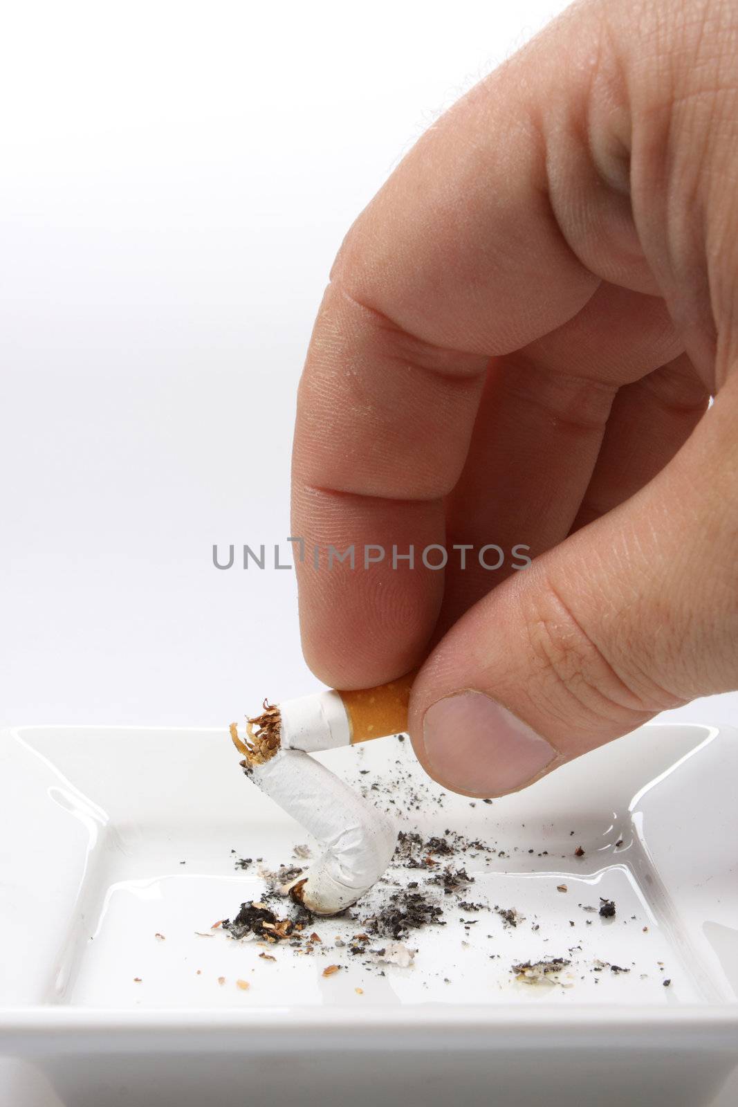 Hand stubbing out a cigarette on white ashtray isolated on white