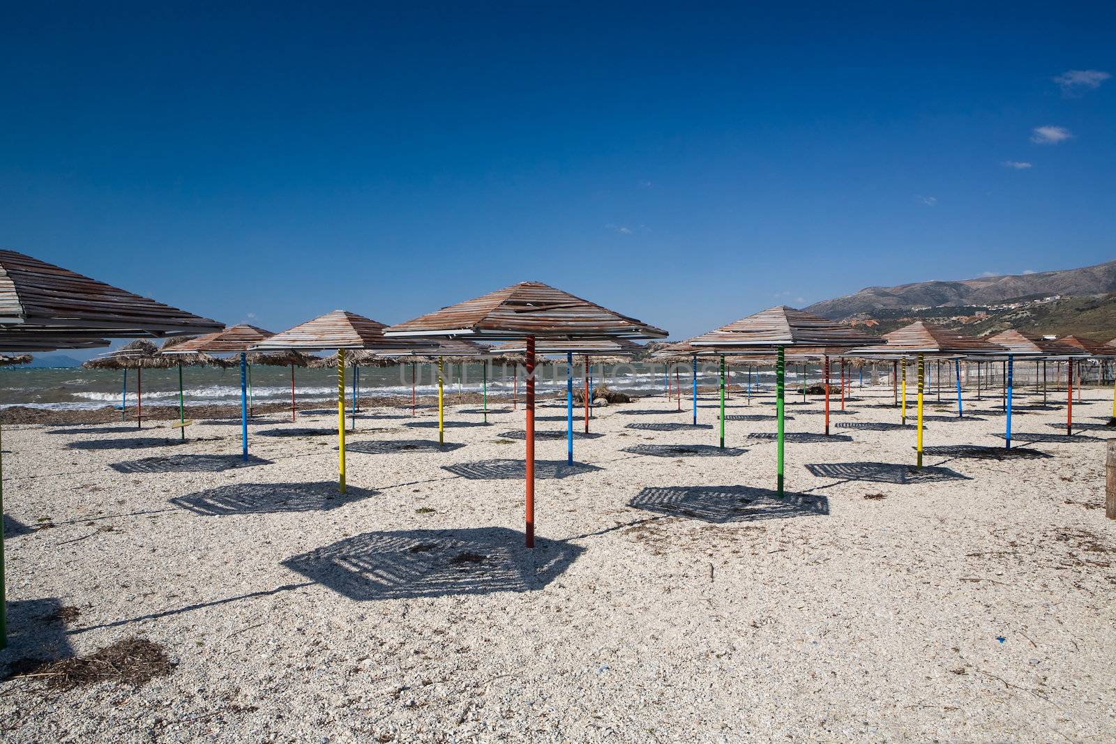 Set of beach umbrellas on sand making shadows under the blue clear sky in hot day