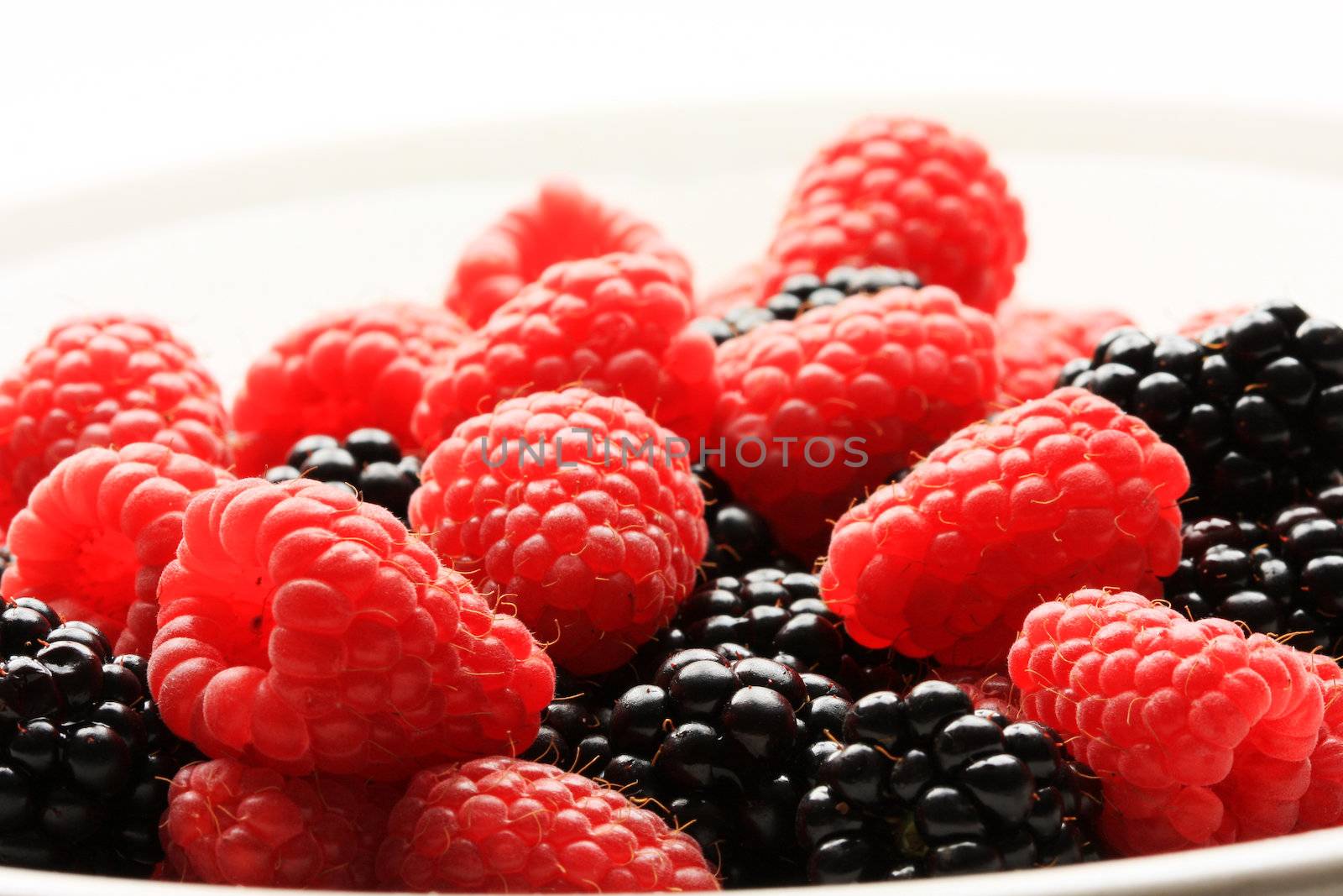 A bowl of raspberries and blackberries, shot in studio