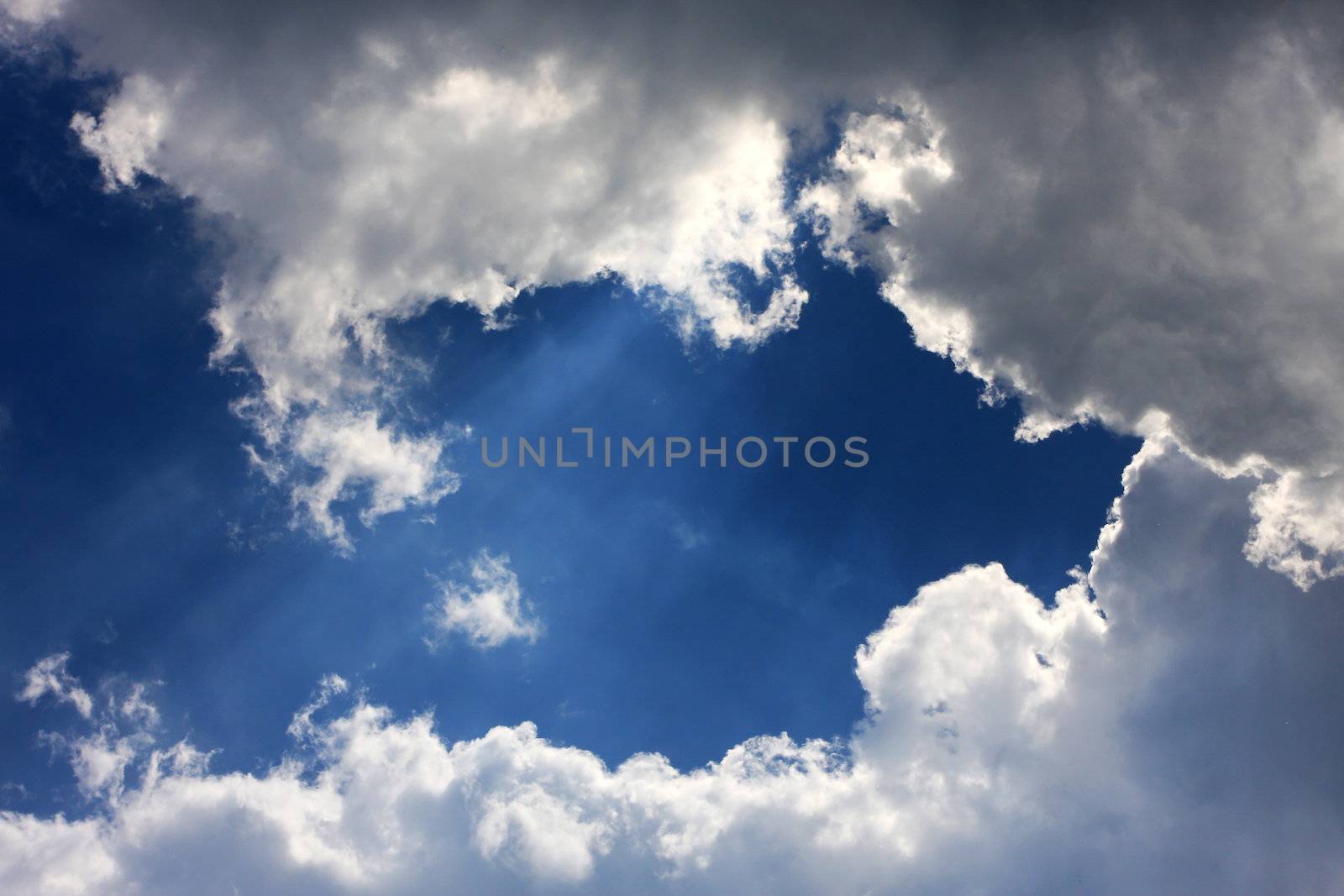 fantastic cloudscape on a blue sky, sun shining behind the clouds great for backgrounds or messages