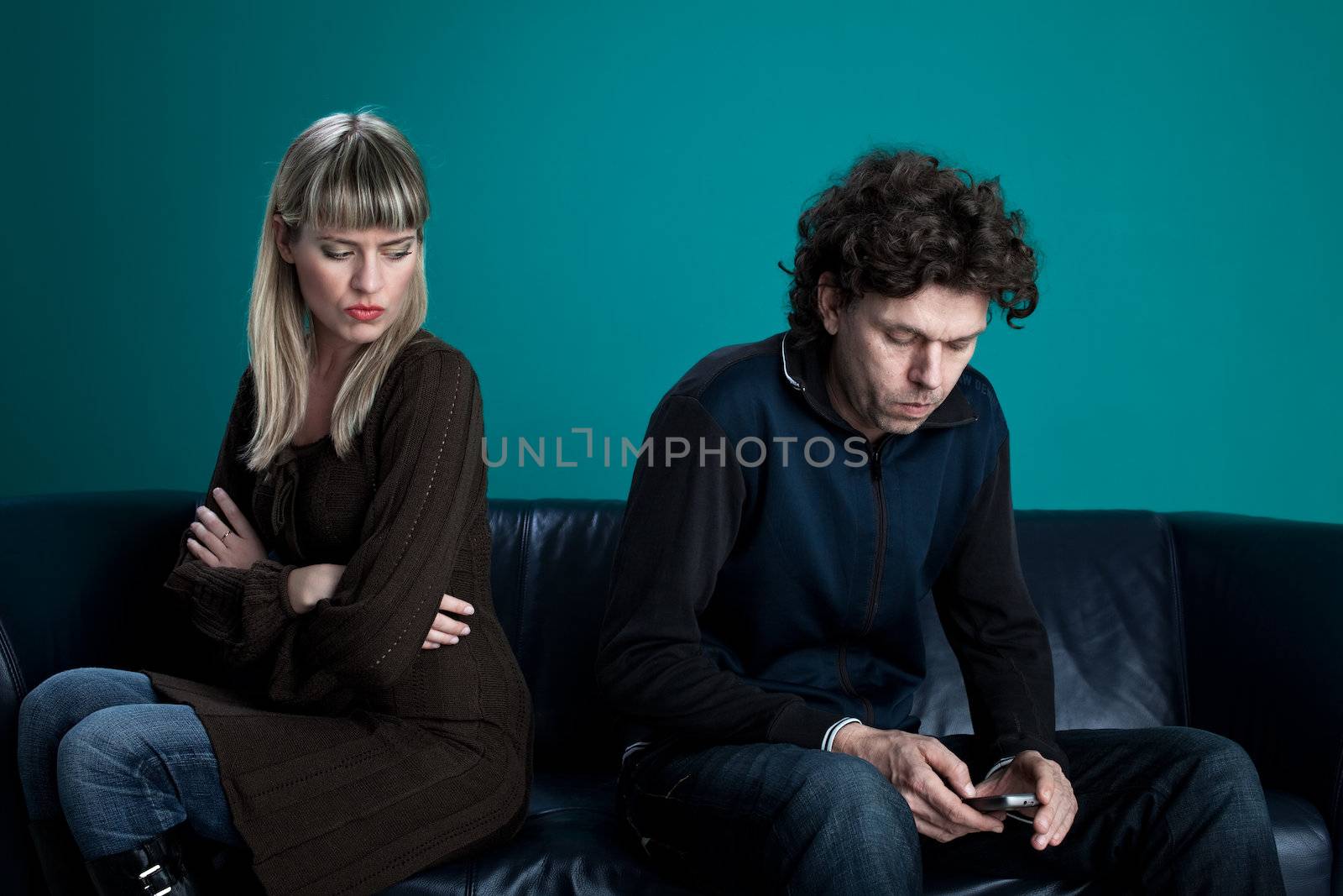 couple on a black leather couch with a cell phone