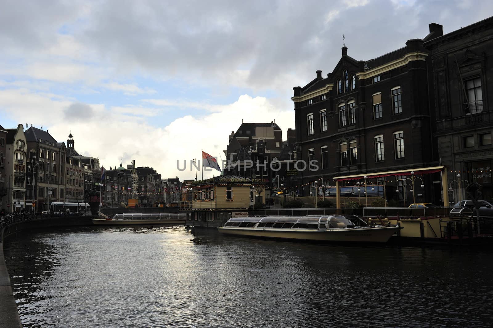 canal water reflecting Dutch buildings boats clouds and blue sky 