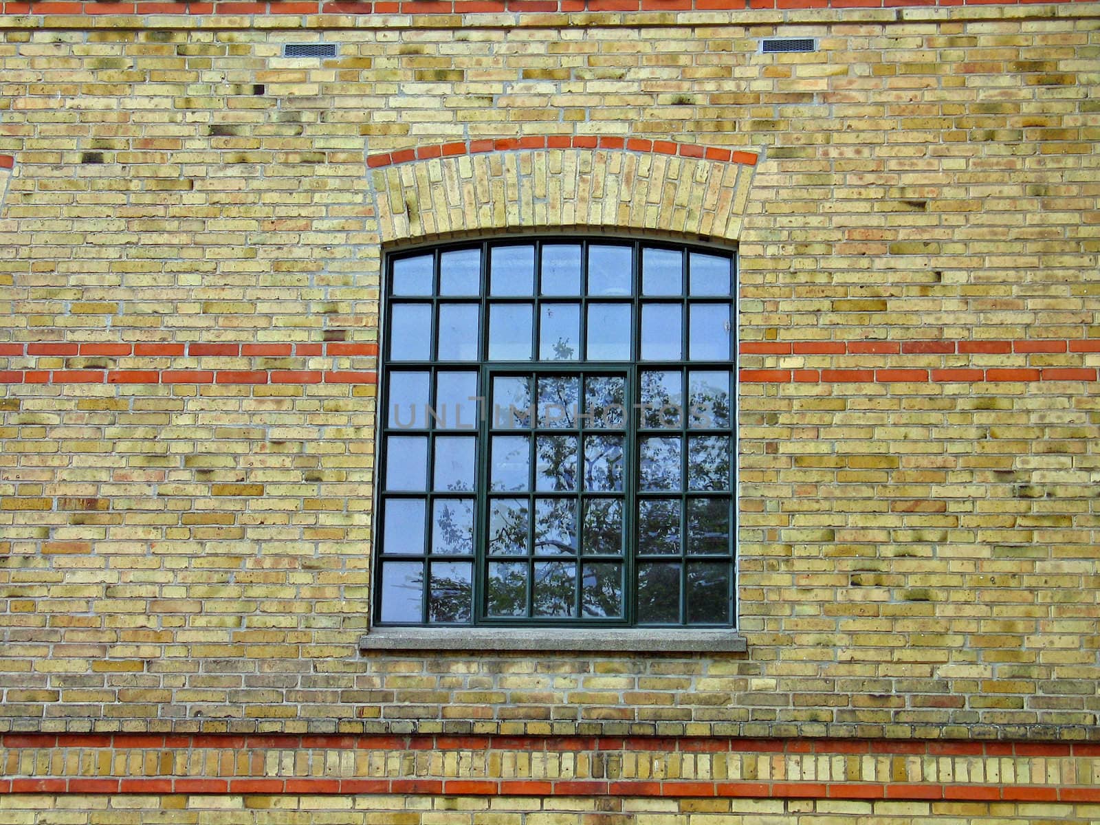 Yellow earth colors bricks wall and a window with reflection