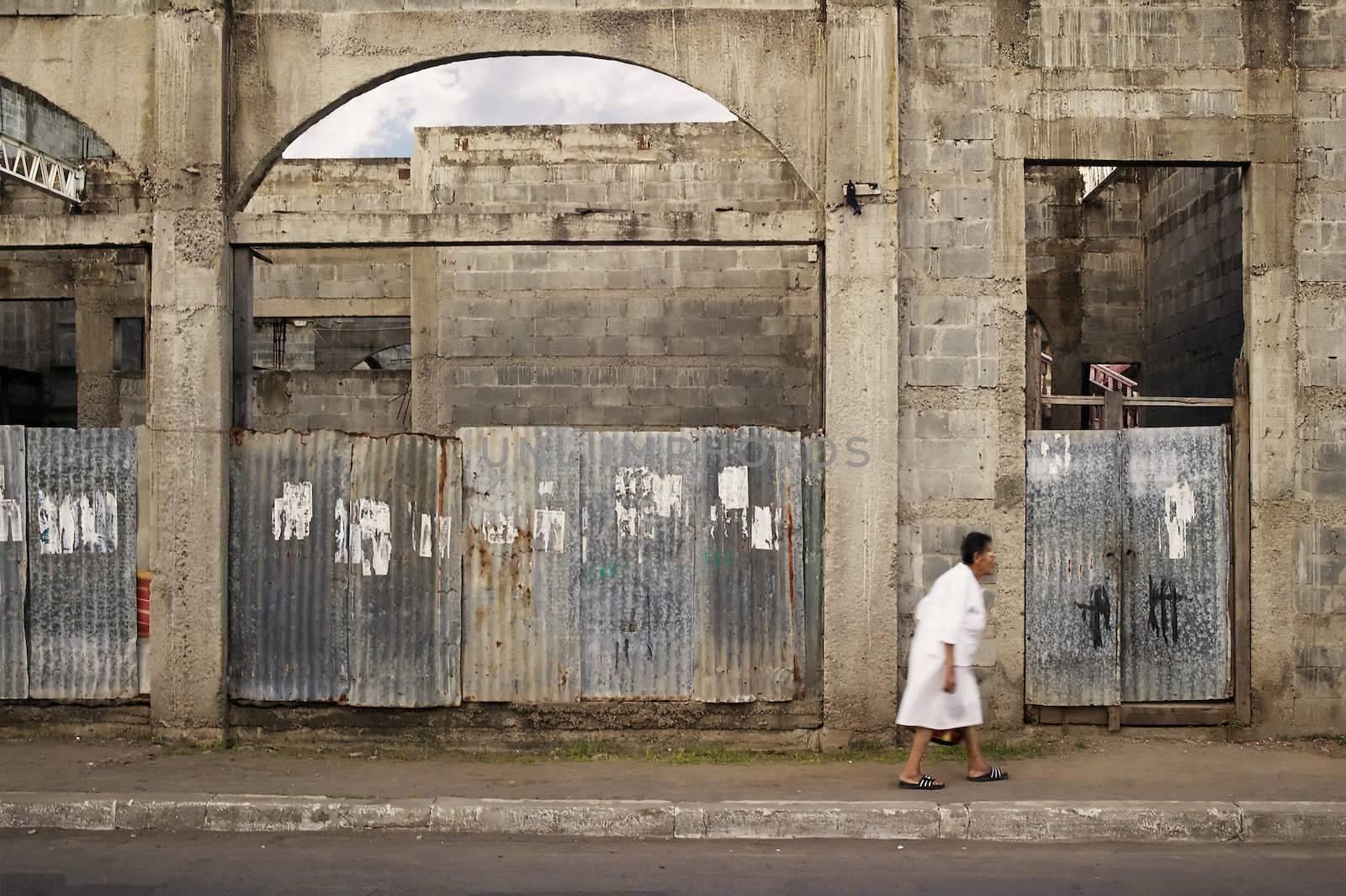Old woman walks by a ruined building in Granada Nicaragua