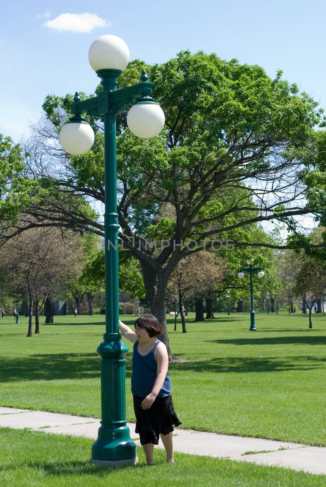 A young girl spinning around a light pole