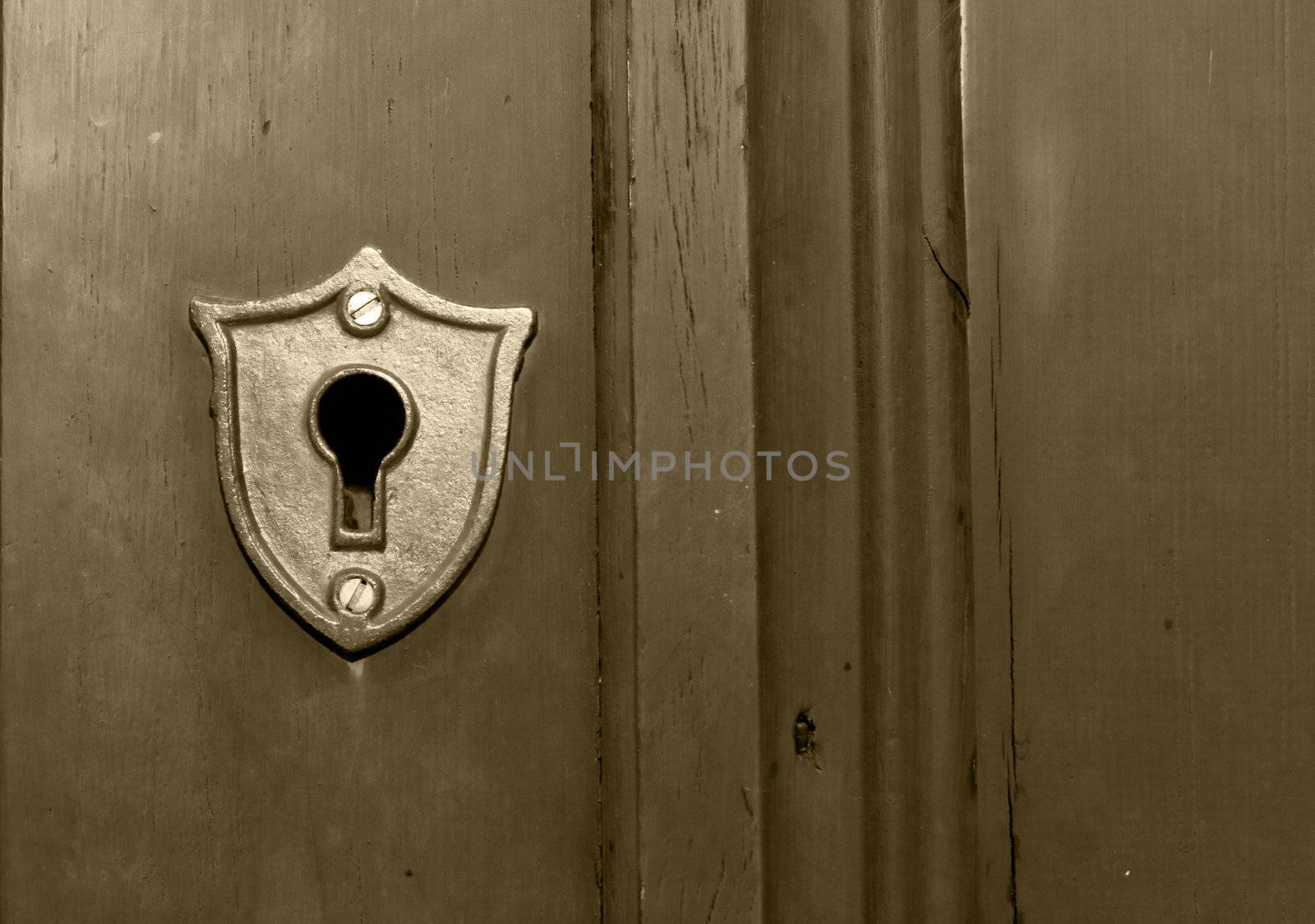 An old fashioned key hole built into a wooden door