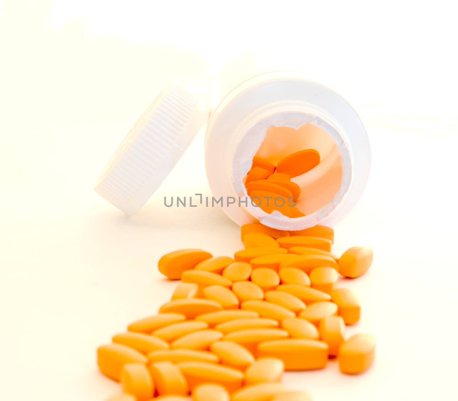Healthy vitamins pouring out of a container, isolated on a white background