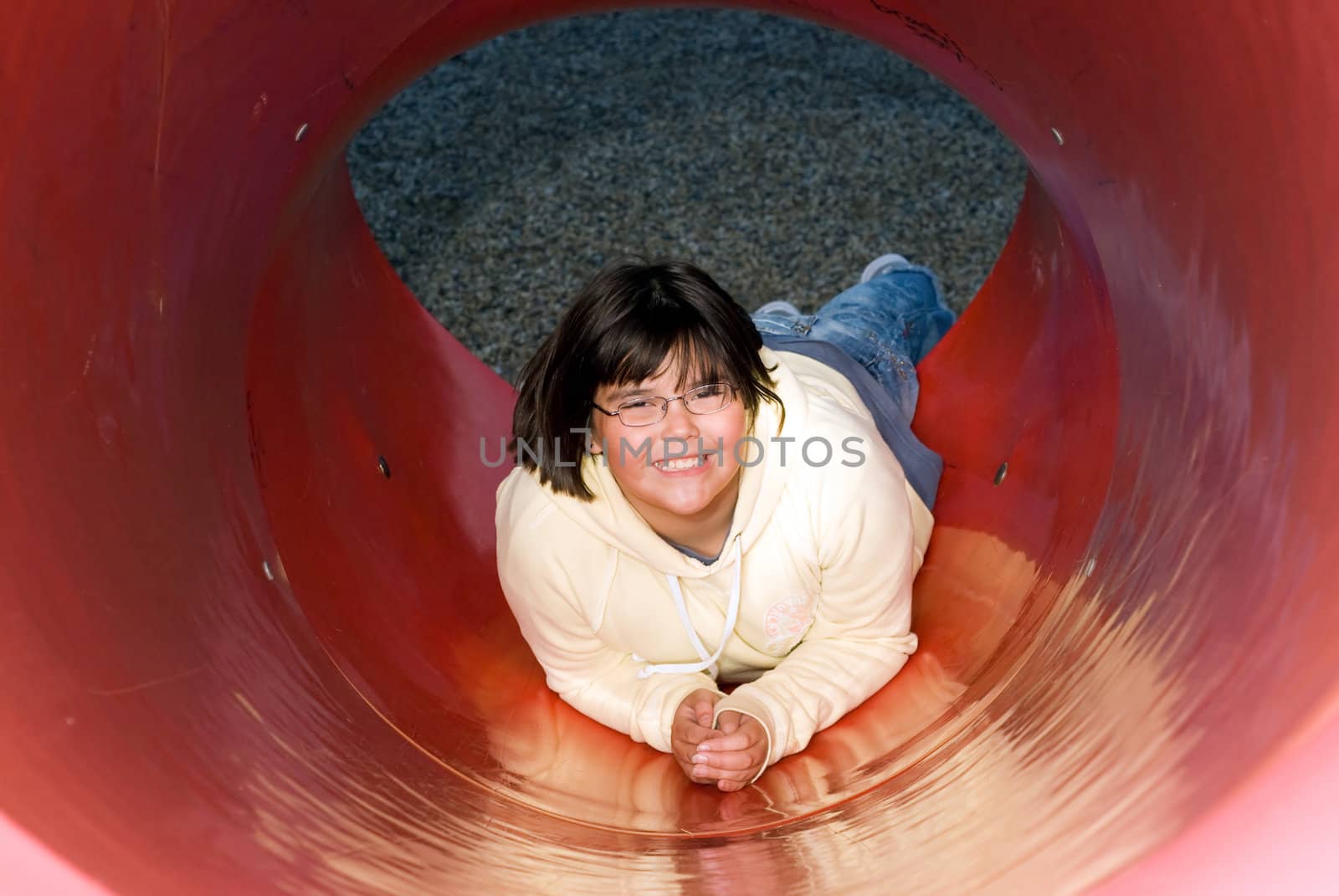 A young girl playing on a red slide in a park