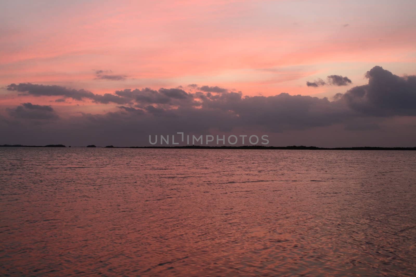 The sky and water turning pink during a sunset.