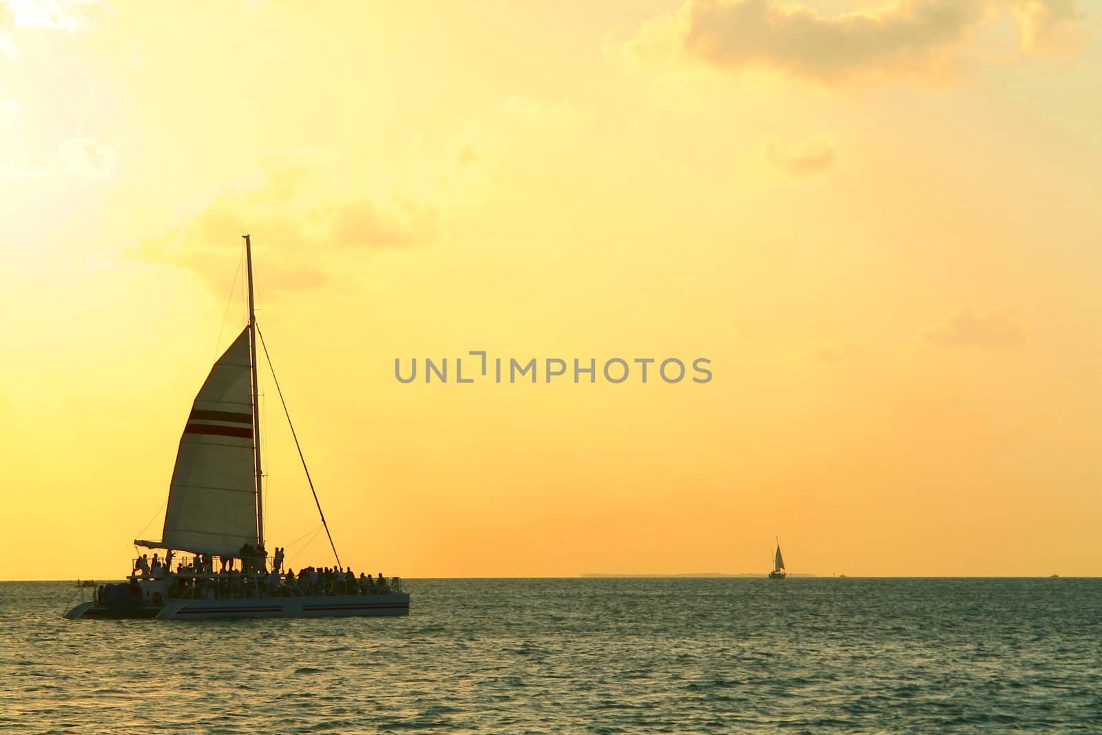 A Sailboat crosses the horizon under the evening sky.