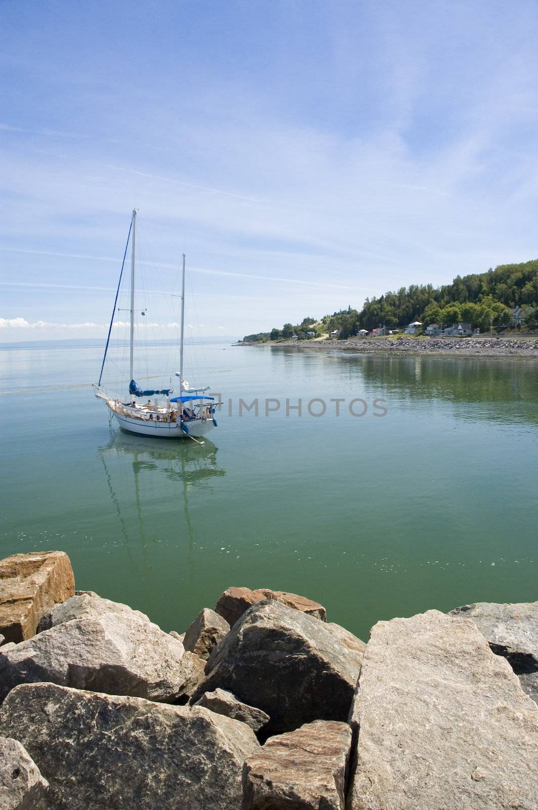 Sail boat on a calm river surrounded by a mountain