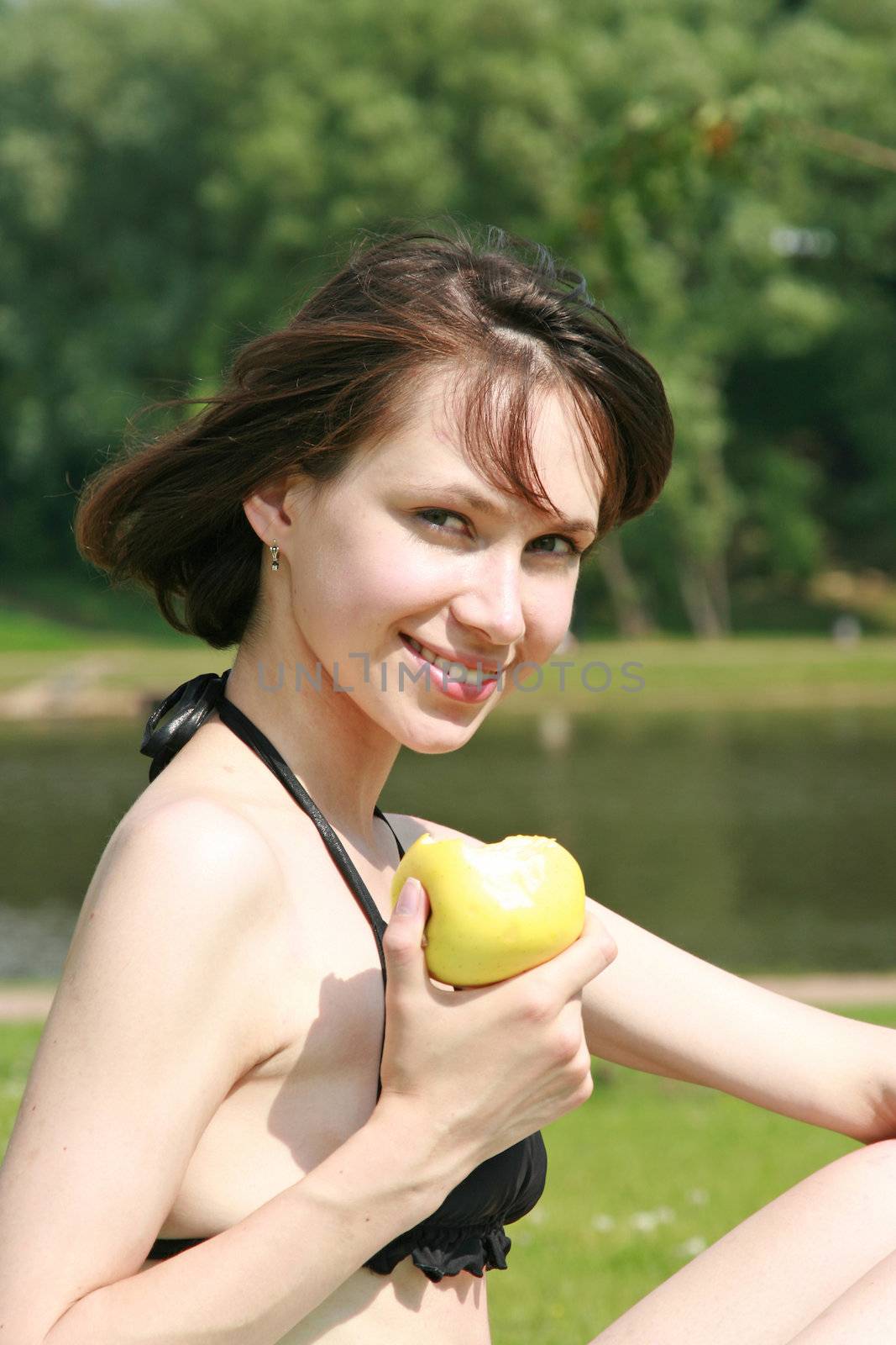 The beautiful girl in bikini eats an apple