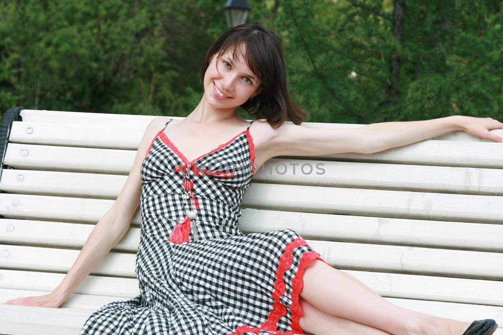 The beautiful girl poses on a bench