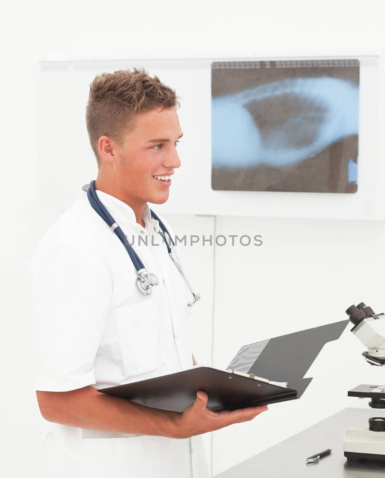 Smiling young doctor with phonendoscope having good news about patient diagnosis;