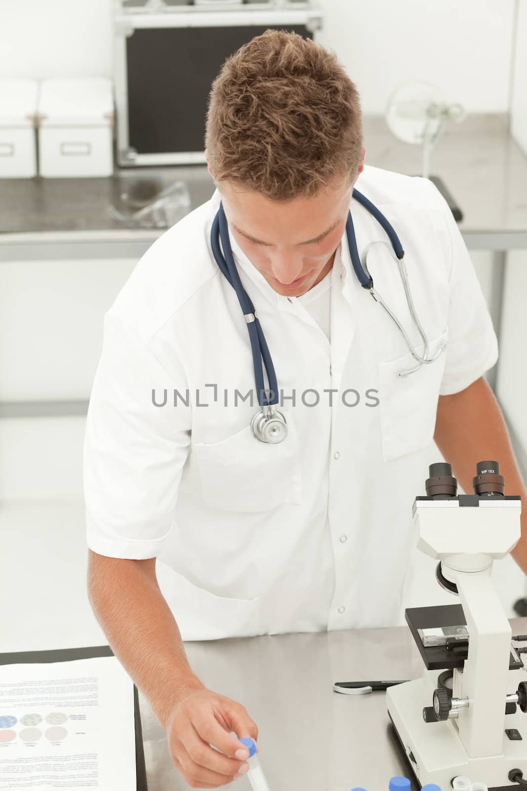 Young blond handsome doctor standing in lab, checking results of medical tests