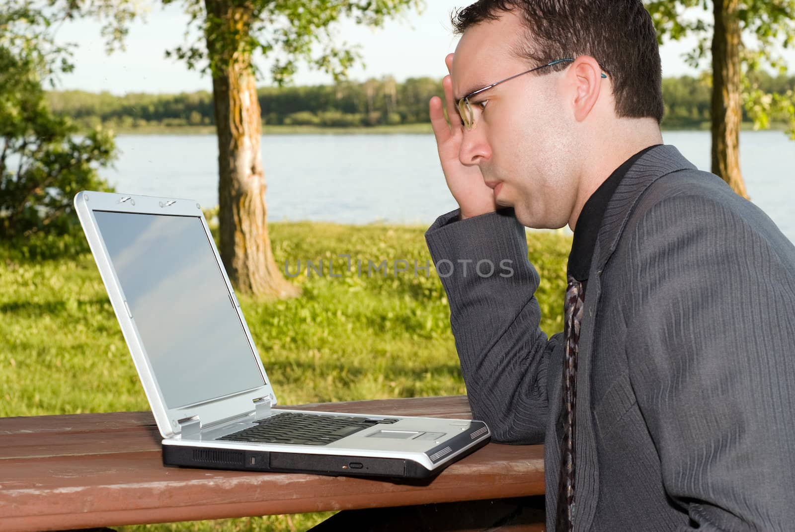 A young businessman working on his laptop outside