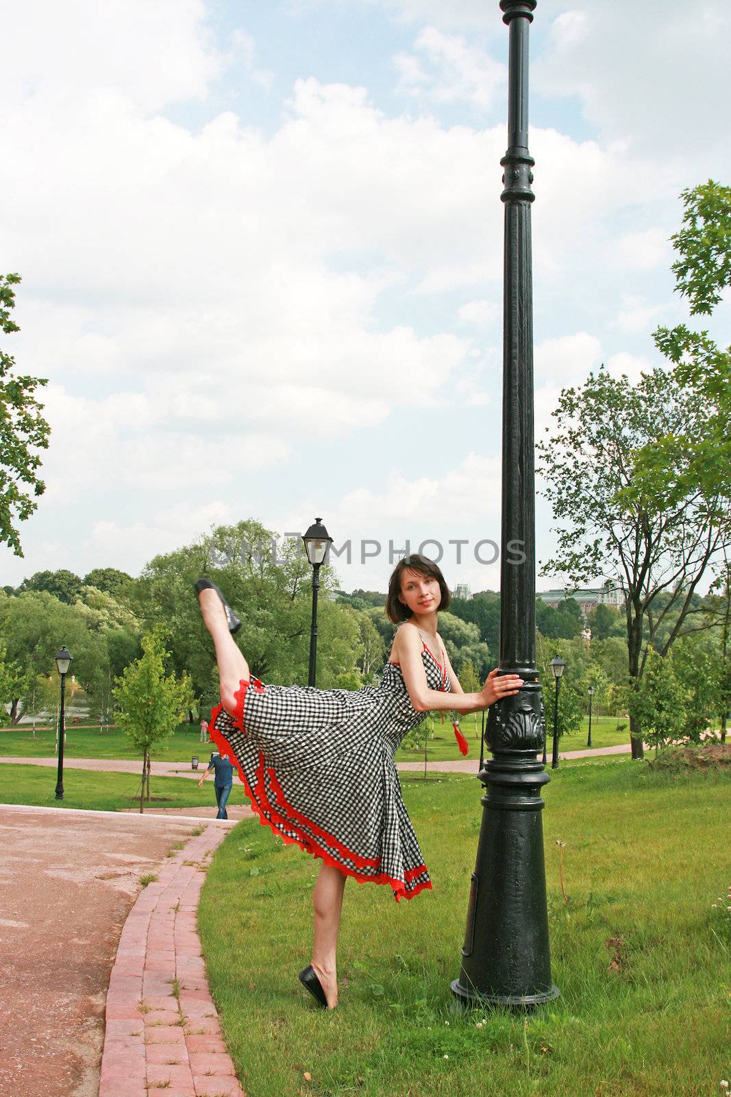 The beautiful girl poses at a lamppost