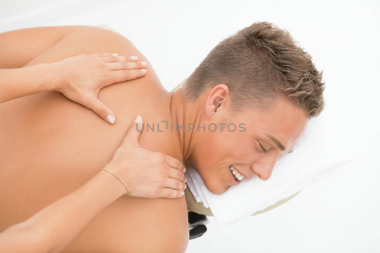 Young blond man enoying massage session in spa resort